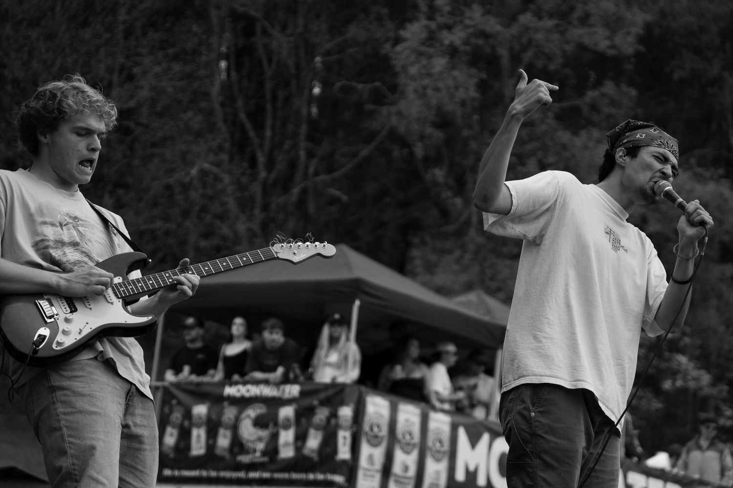 Black and white photo of guitarist and singer performing live on outdoor stage.