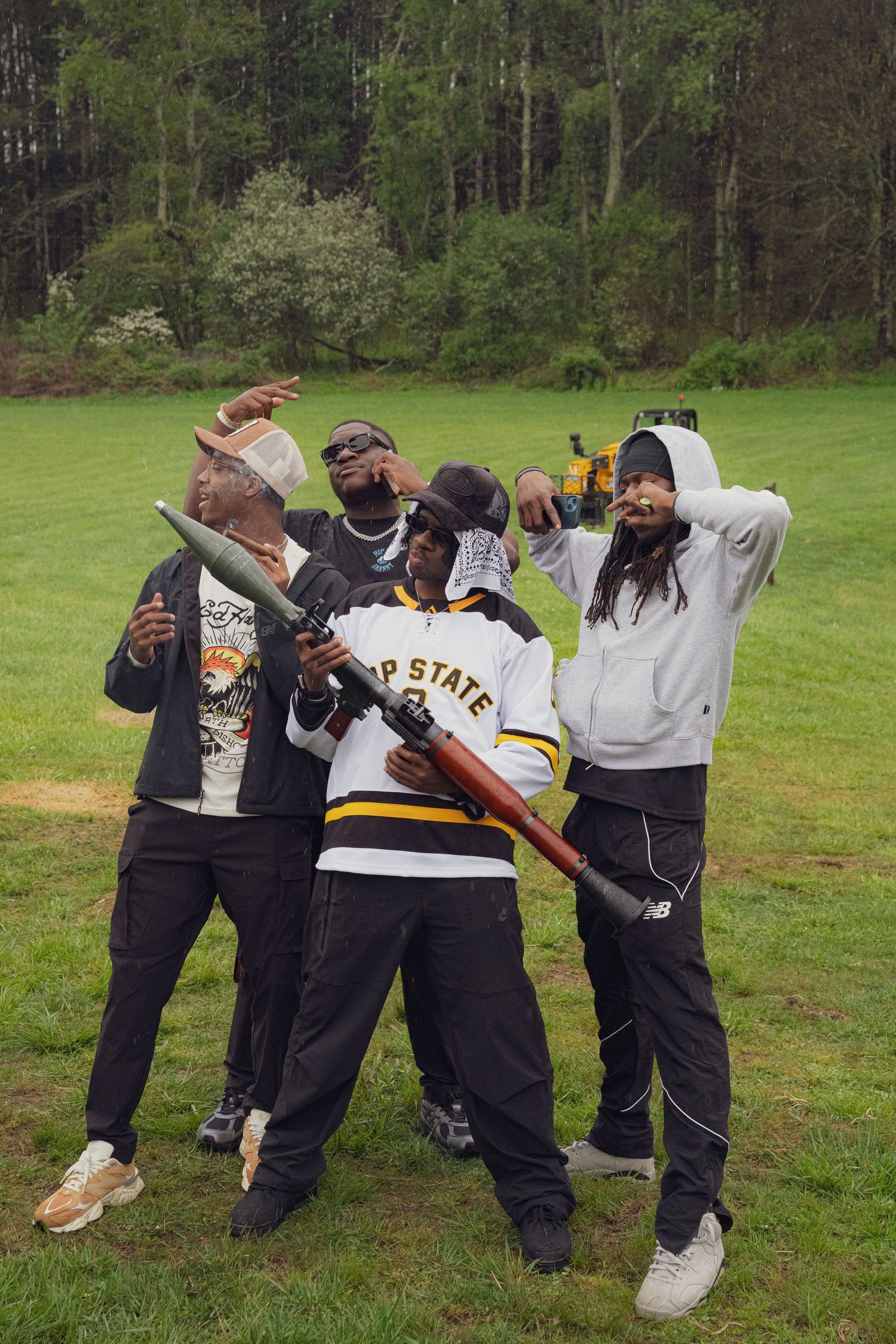 Four friends posing playfully with props on a green field at an outdoor music festival.