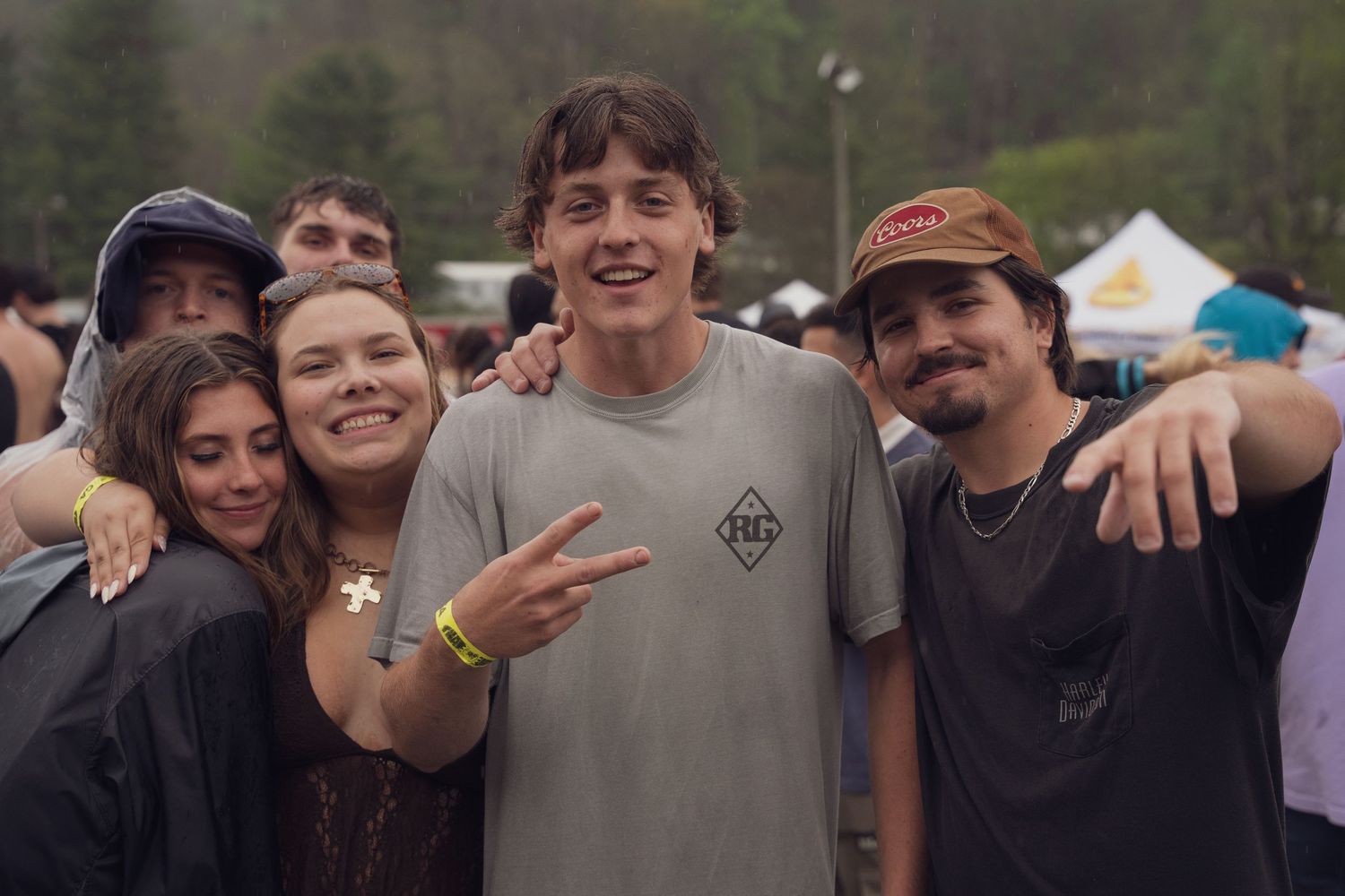 Four smiling friends pose together at an outdoor music festival.