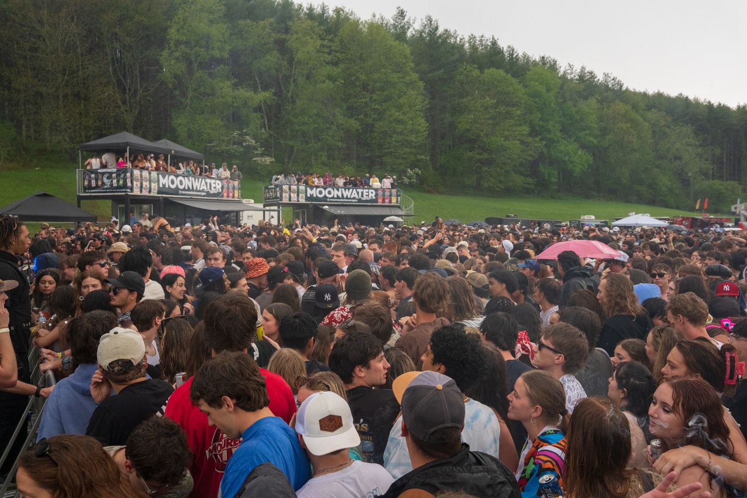 Large crowd gathered in front of Moonwater festival stage surrounded by green forested hills.