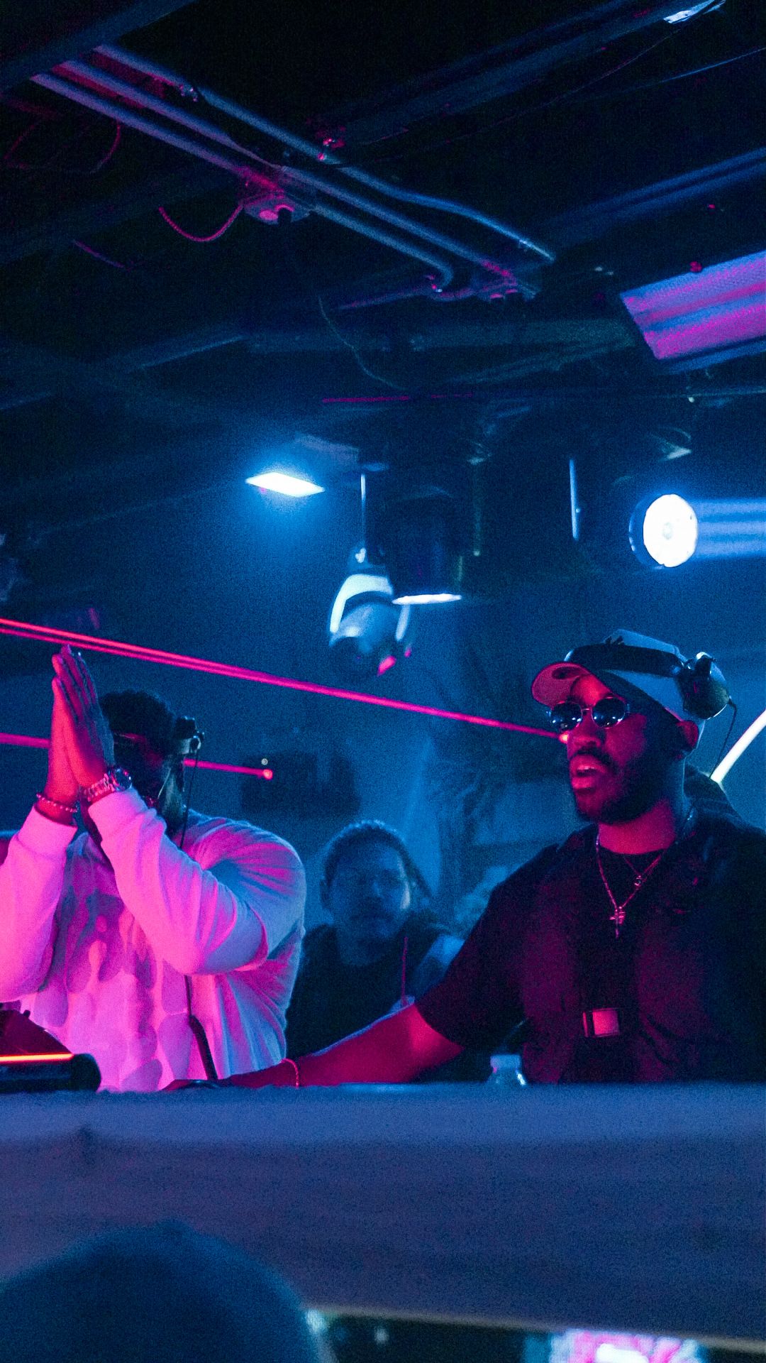 Two DJs performing under pink laser lights at an energetic nightclub event.
