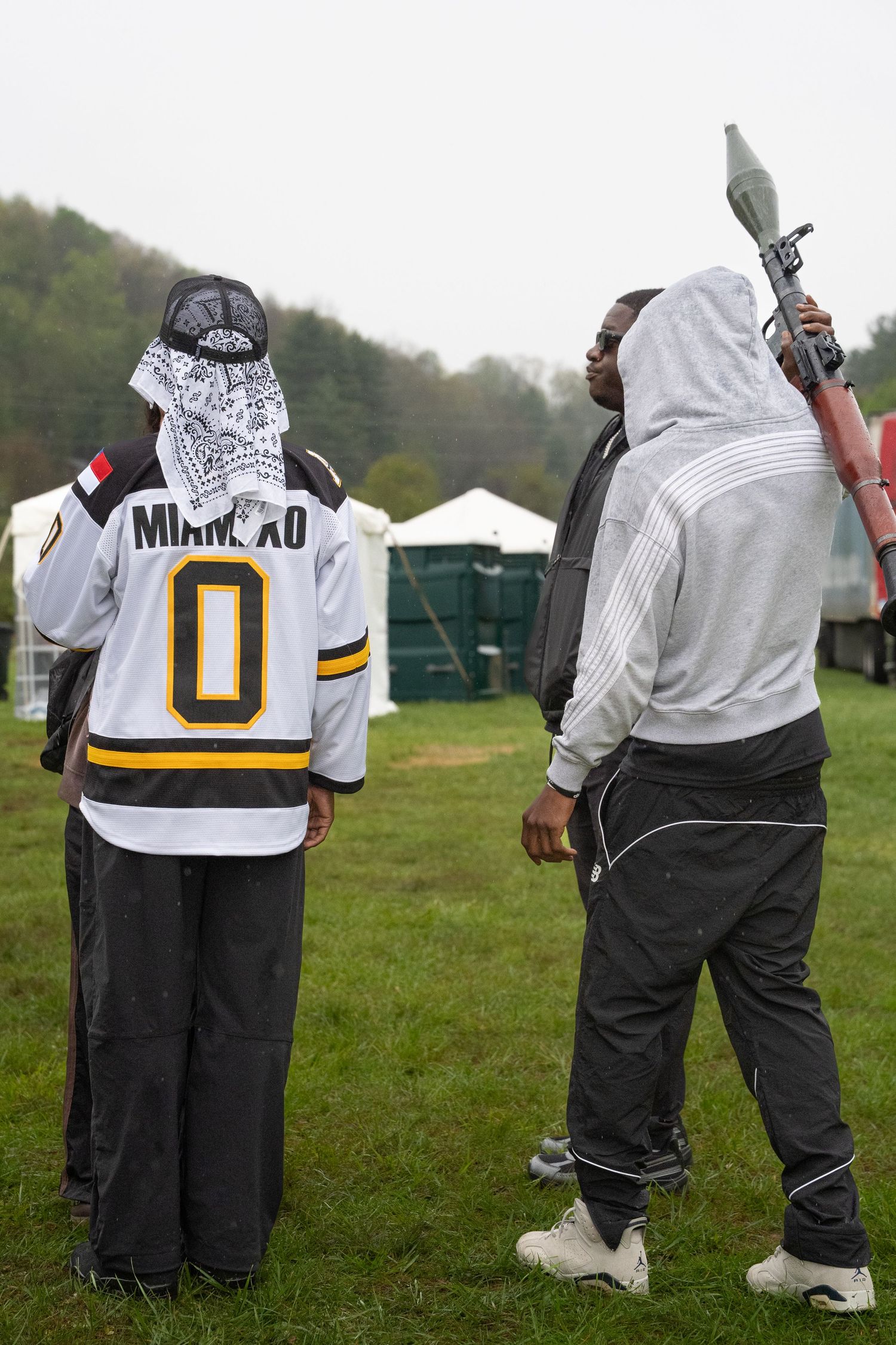 Two people in sportswear and hockey jersey at outdoor music festival on cloudy day.