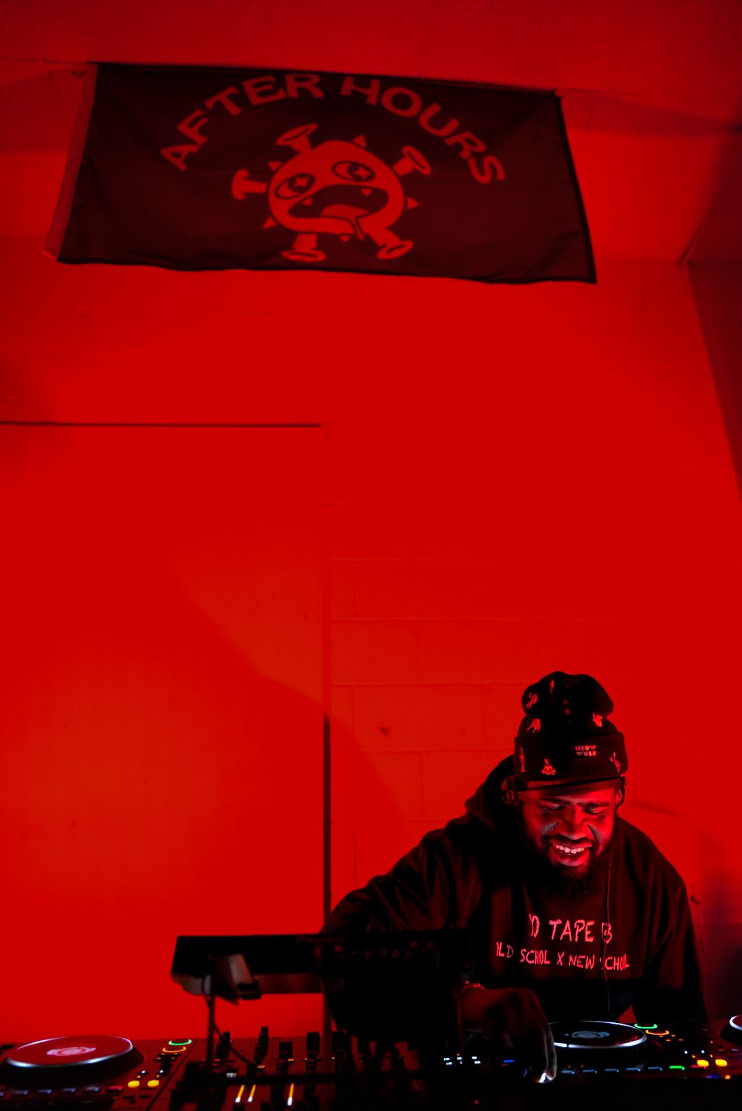 DJ performing under After Hours flag bathed in dramatic red lighting.