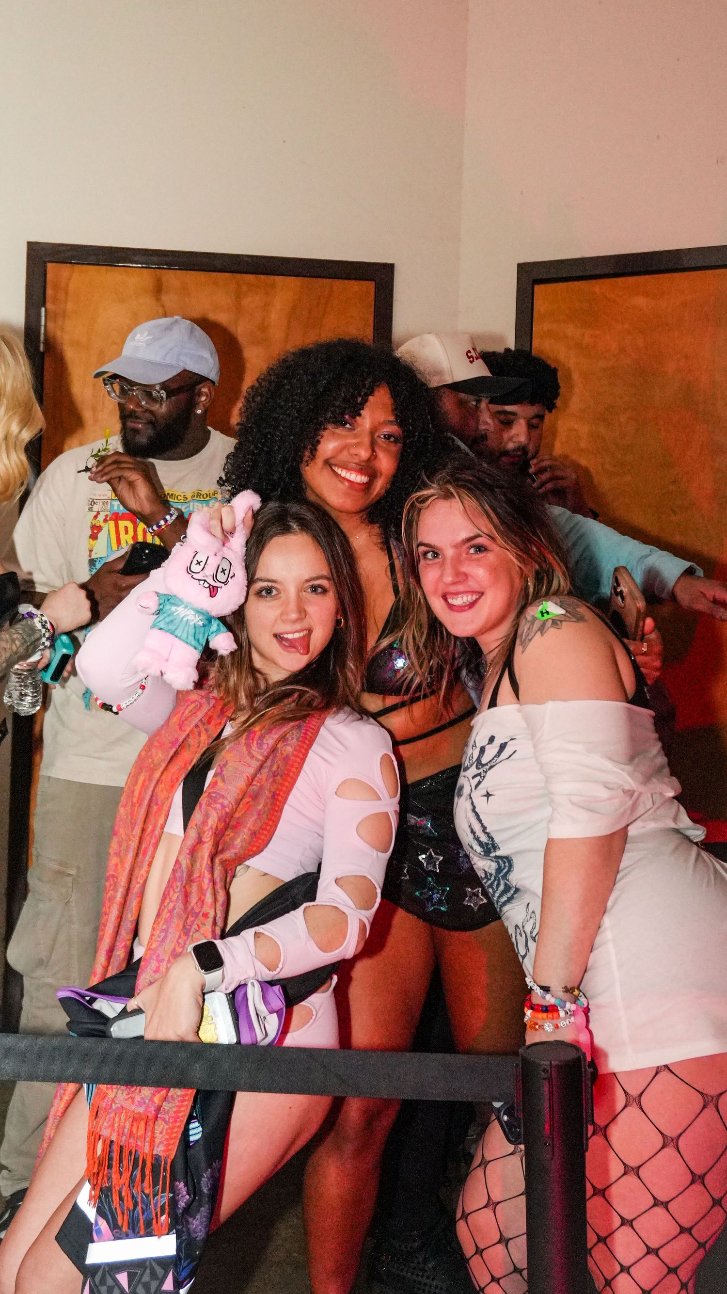 Three young women smiling and posing together at a music festival event.