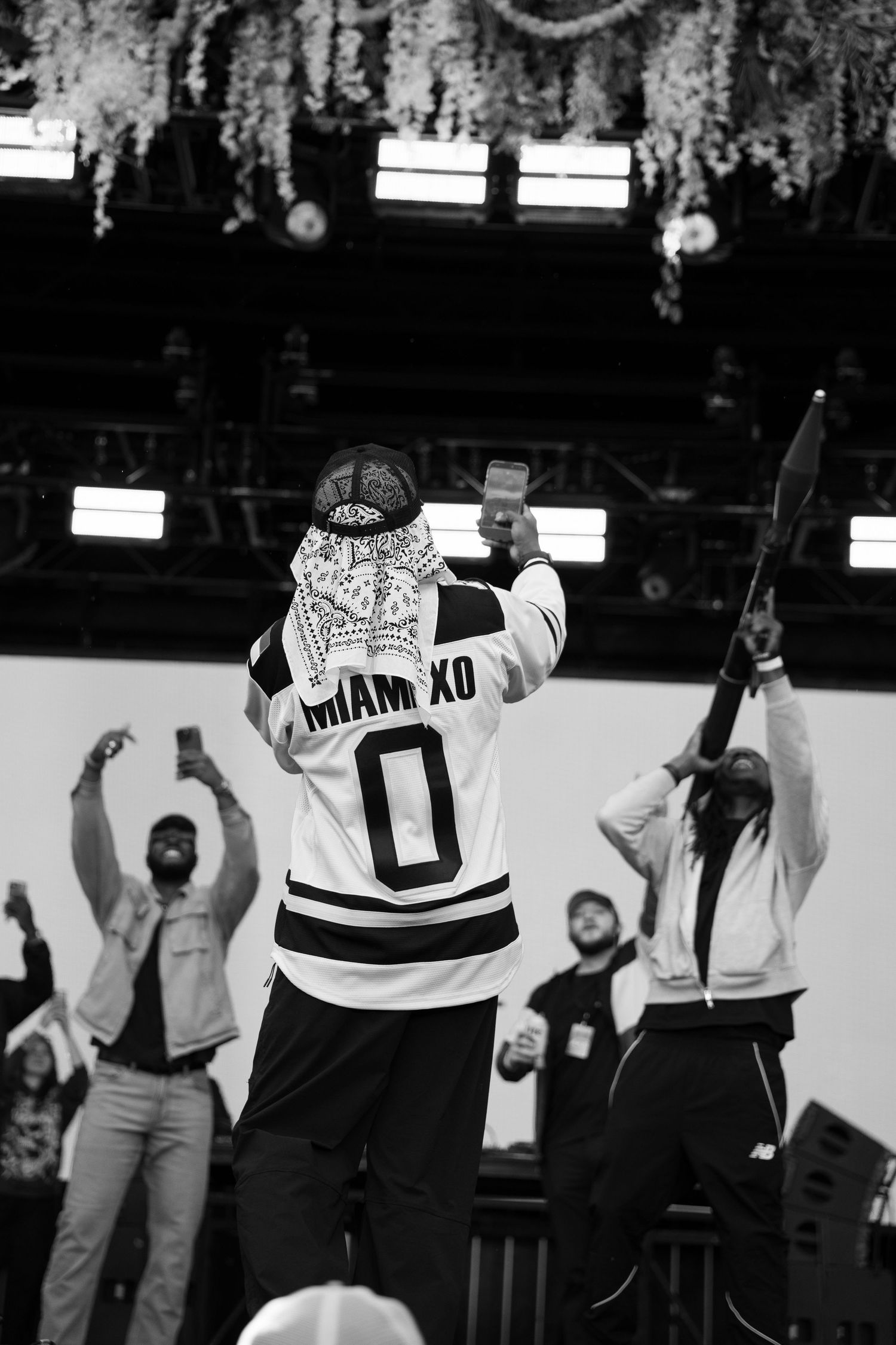 Black and white shot of rapper in Miami XO jersey facing crowd at outdoor festival stage.