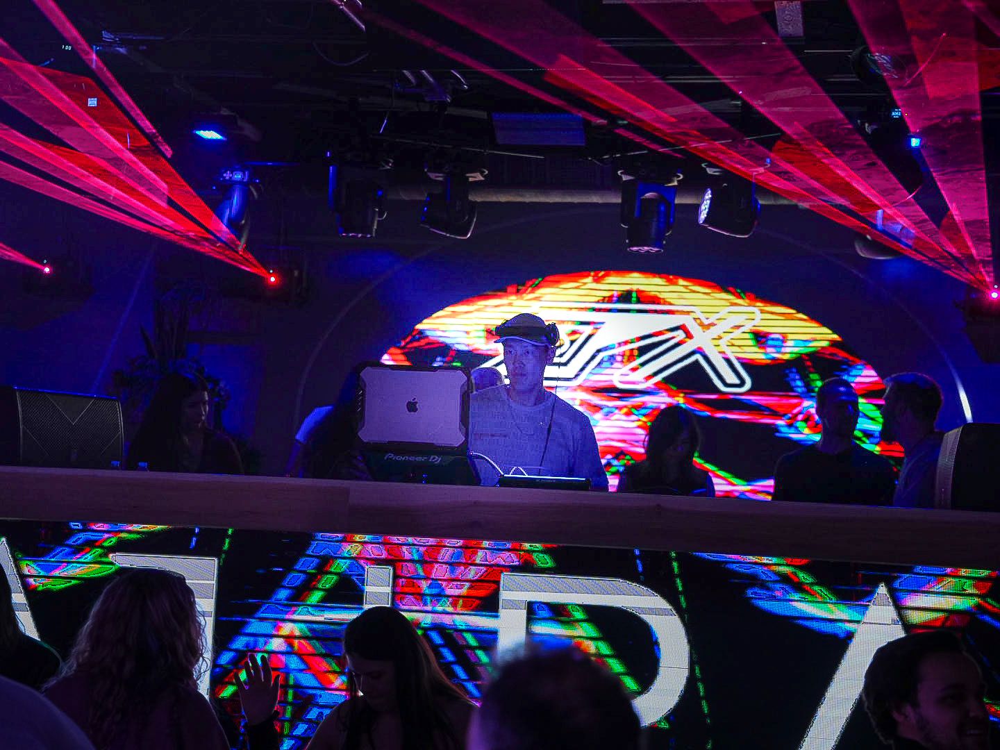 DJ performing on stage at MARA nightclub with colorful laser lights and vibrant LED displays.