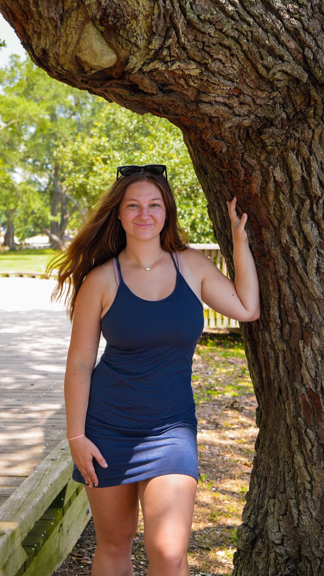 Woman standing next to tree with her hand on the tree