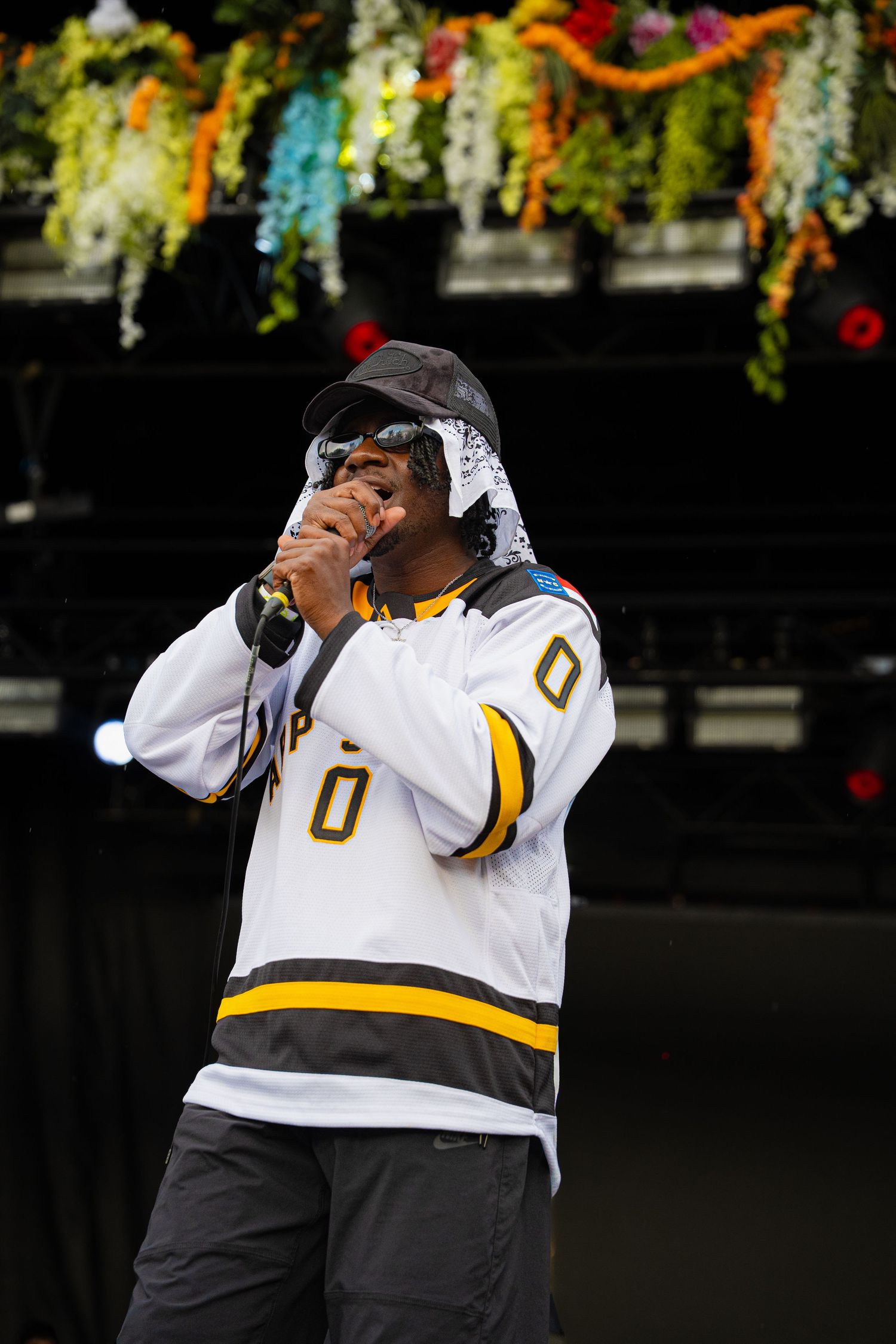 Rapper performing on stage wearing hockey jersey and bandana at festival.