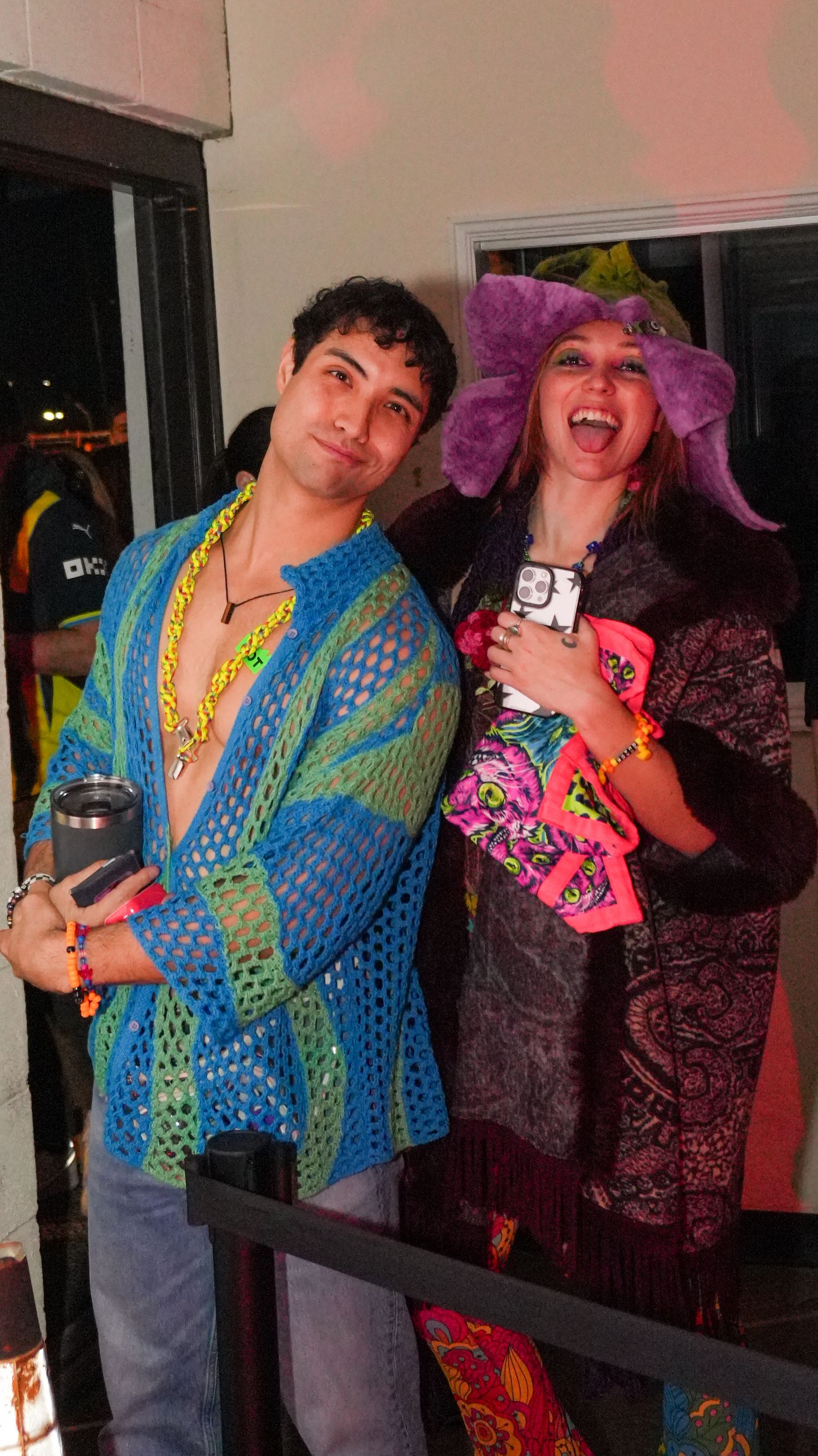 Two people in colorful festival costumes posing together at a party event.