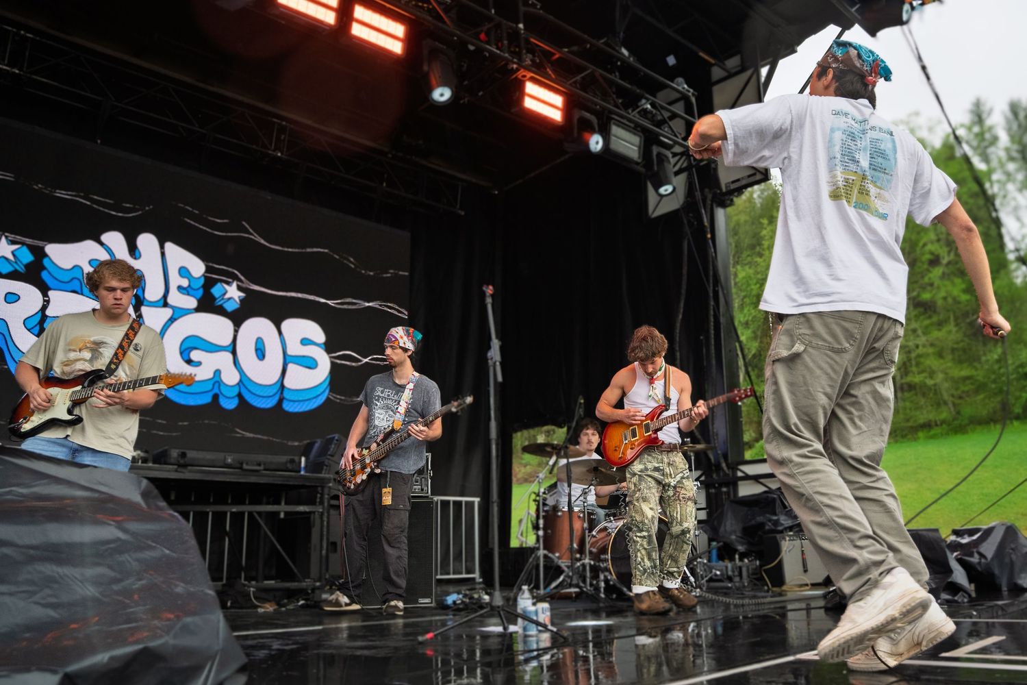 Band The Gringos performing on wet outdoor festival stage in the rain.