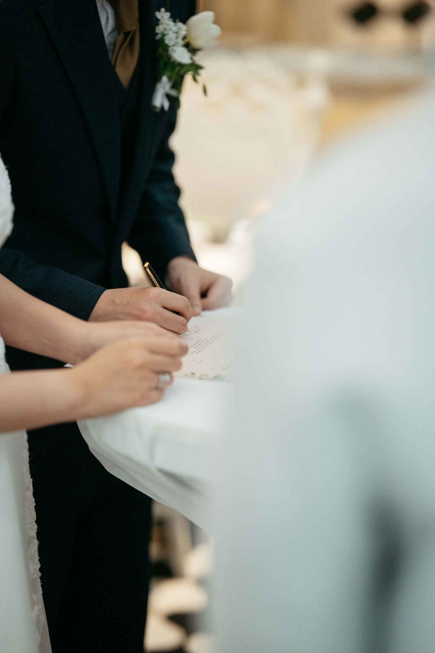 Close-up of hands during a wedding ceremony signing moment.