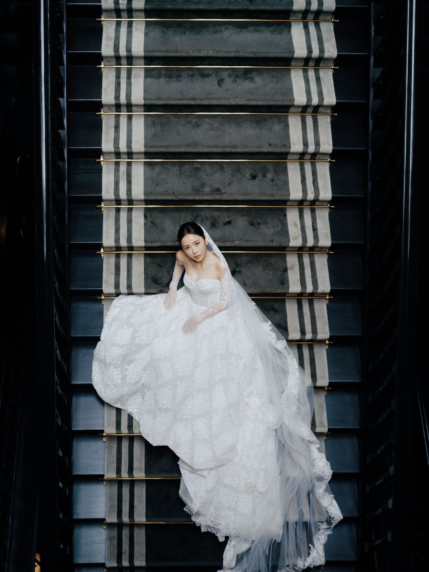 White wedding dress flowing down dark stairs in a dramatic fashion sequence.