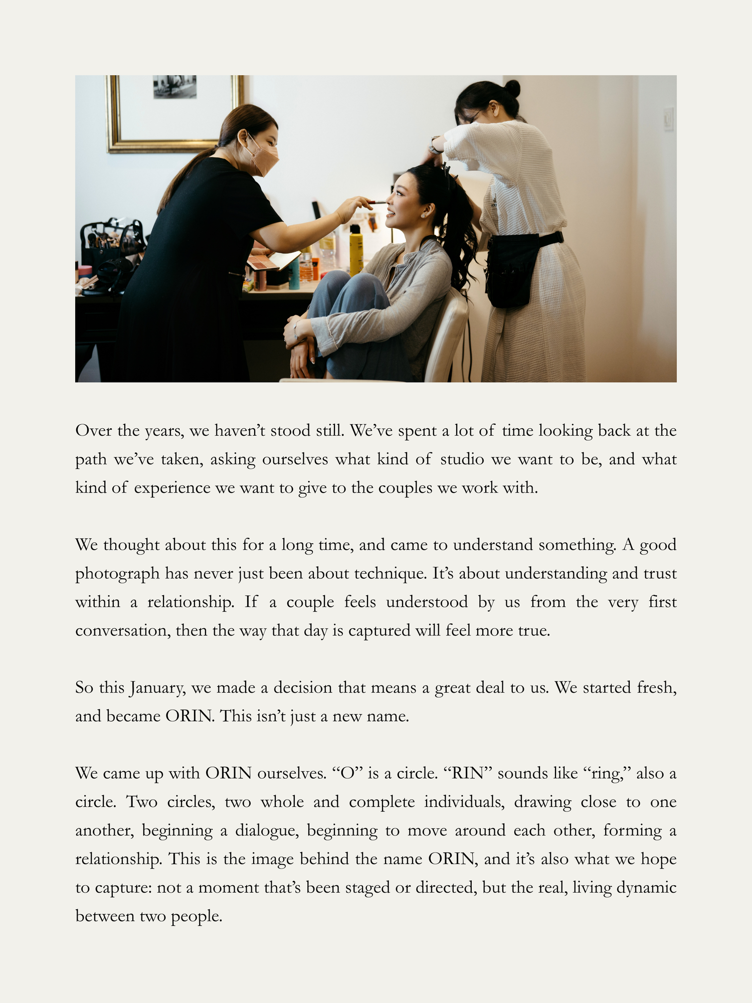 A photographer adjusts a bride's hair in a bright studio, capturing an intimate behind-the-scenes wedding preparation moment.