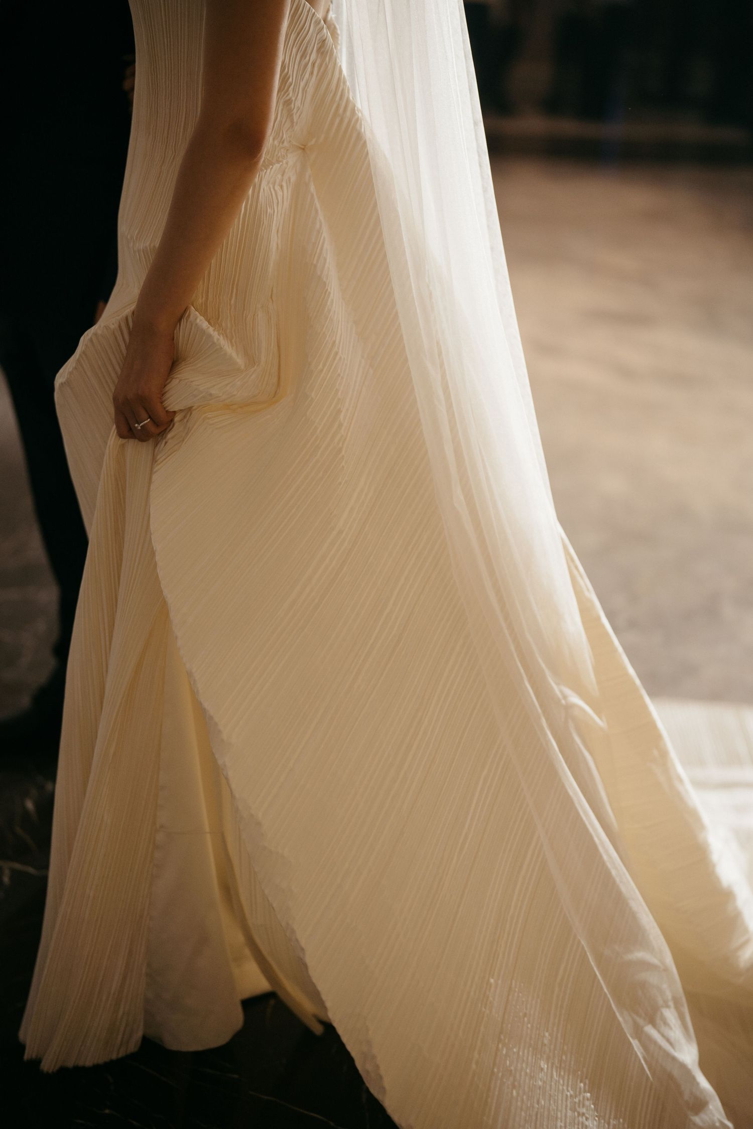 Close-up detail of flowing white wedding dress fabric in warm natural light.