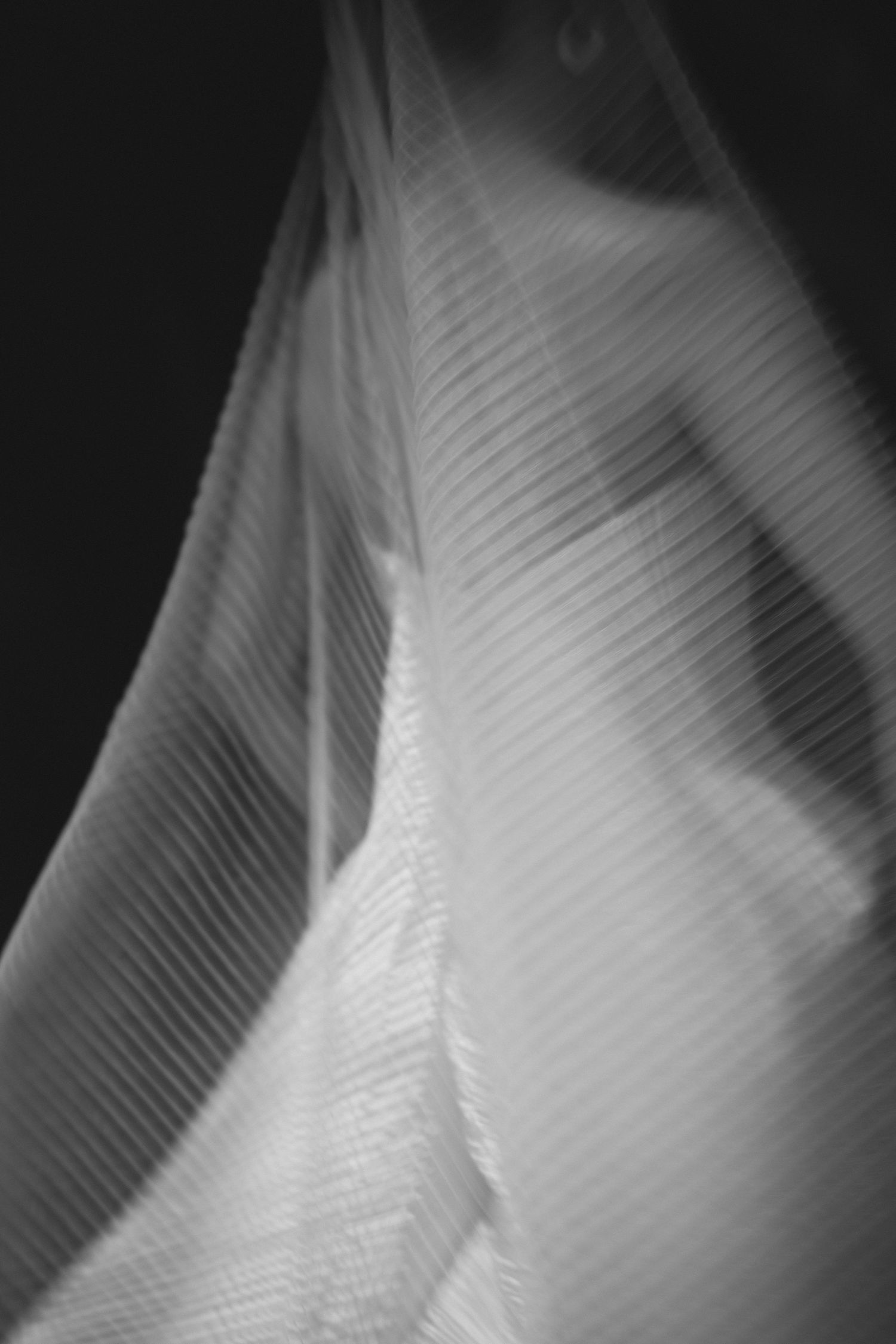 Abstract black and white close-up of pleated wedding dress fabric creating geometric patterns.