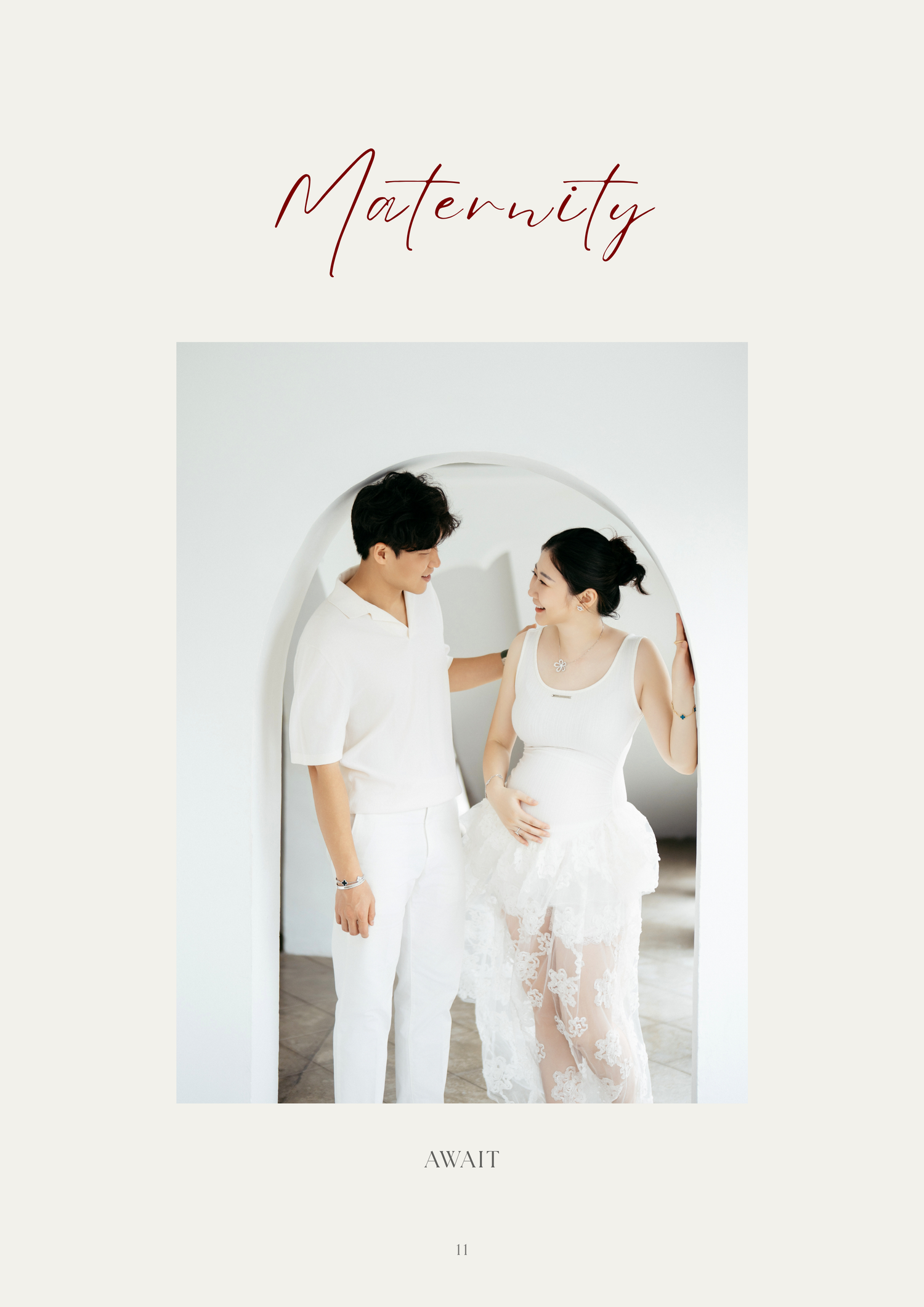 A couple in white outfits poses together under an arched mirror in a bright maternity photo shoot.
