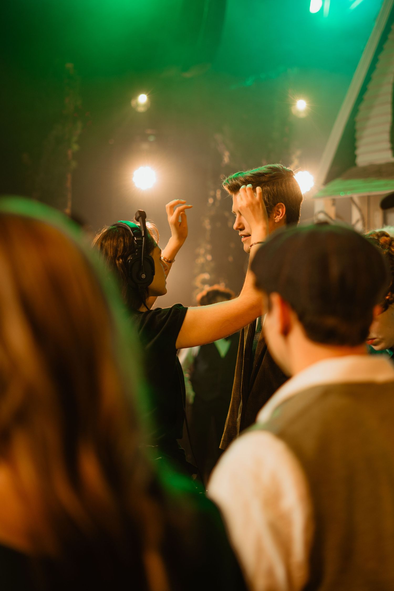 Energetic concert crowd dances under green stage lights at an indoor live music event.