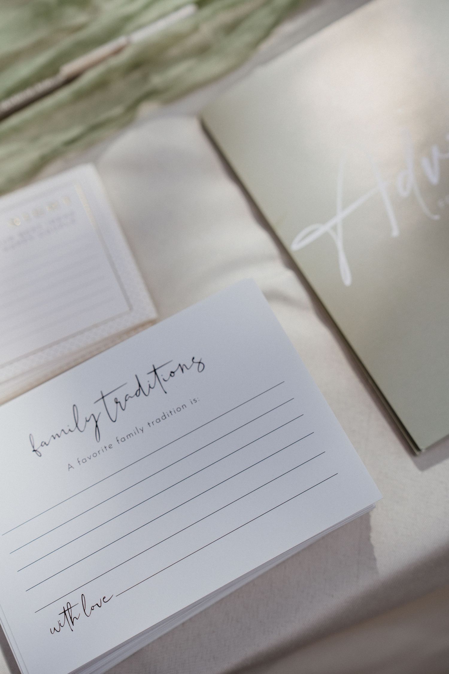 Elegant wedding stationery featuring a family traditions card and vow book on a soft neutral table.