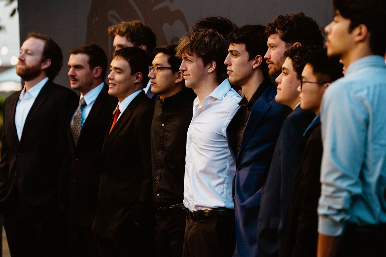 A row of young men in formal attire standing together at an event or ceremony.