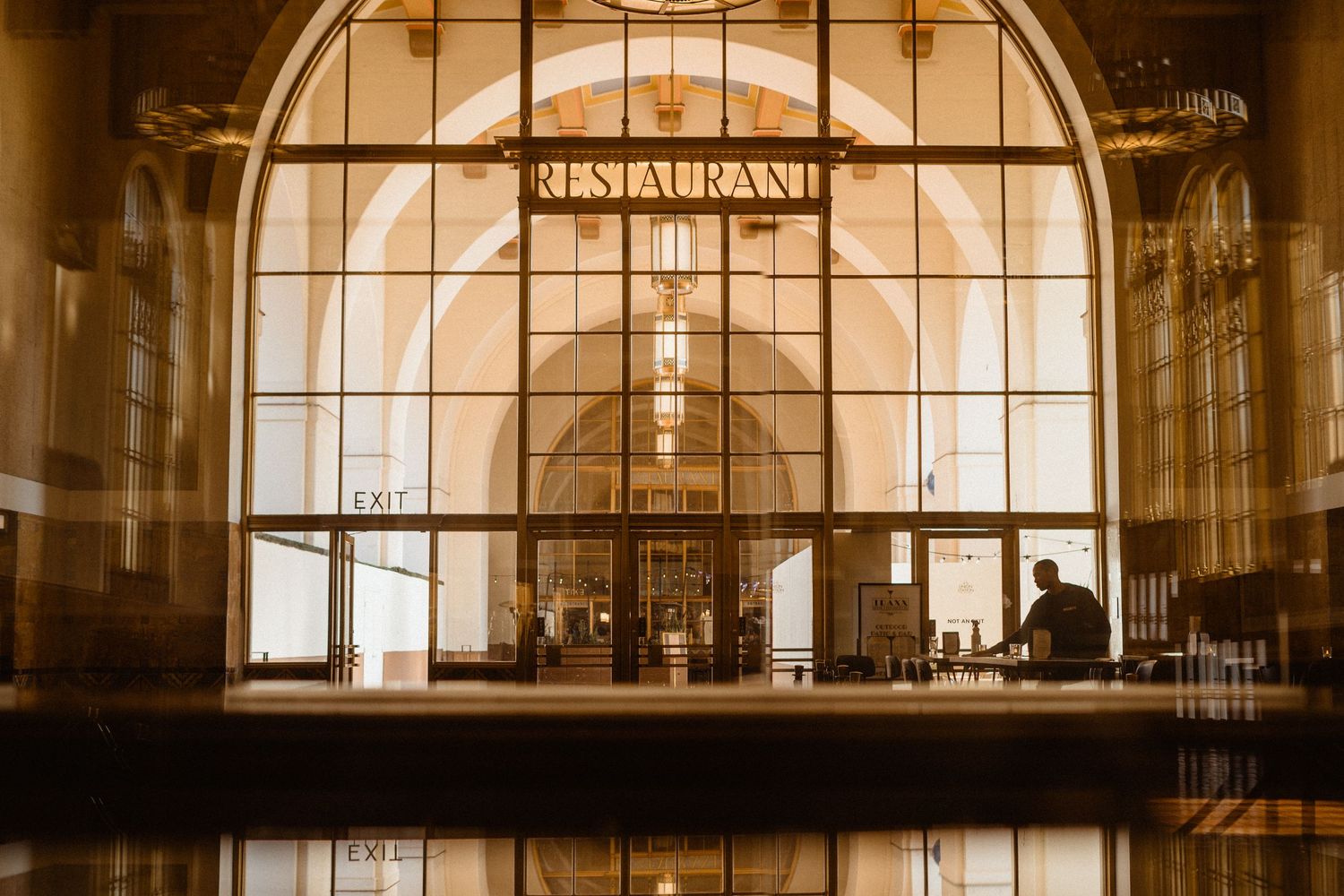 Golden-toned exterior of a historic restaurant entrance with large arched windows.