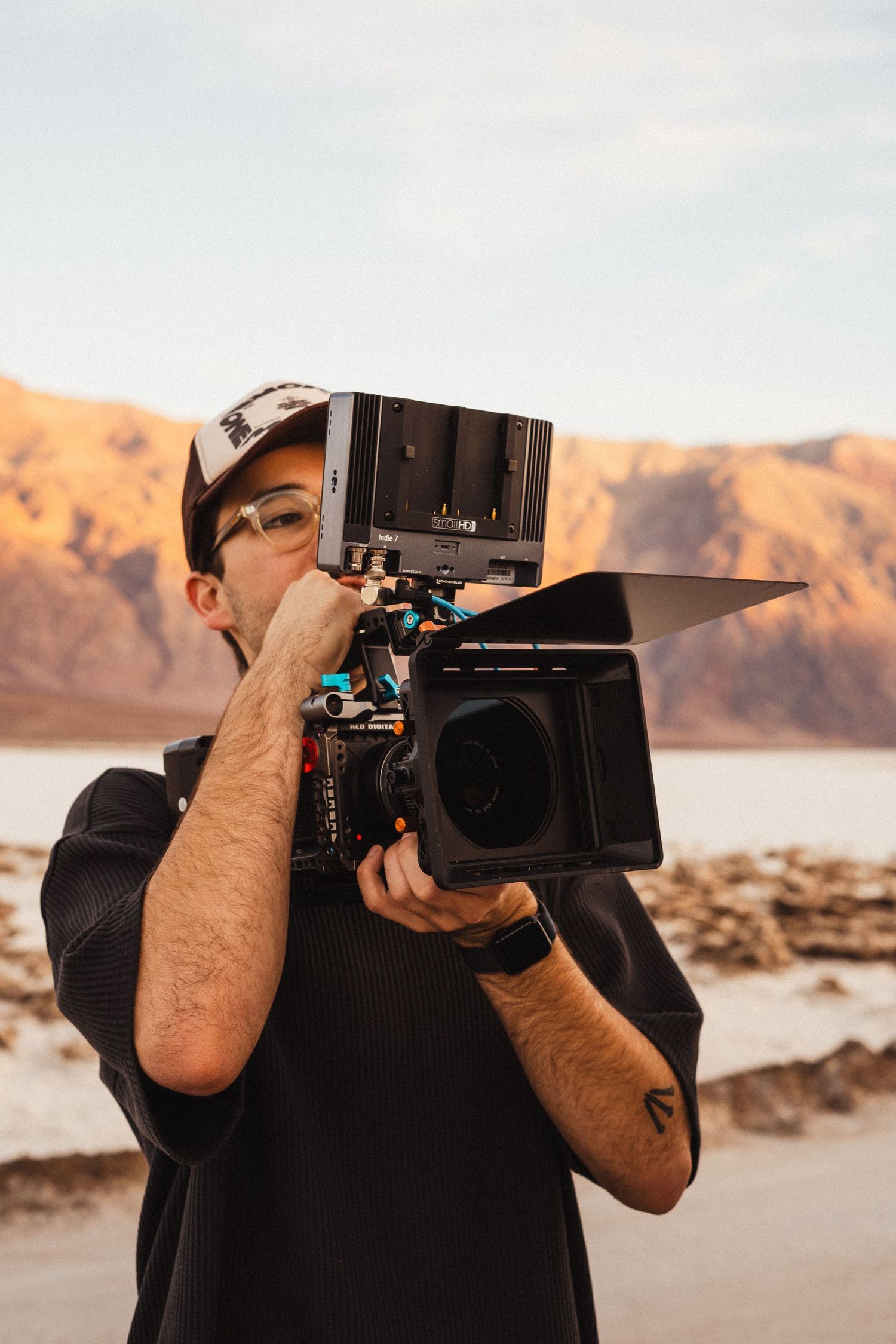 A cinematographer films on location at a salt flat with a professional cinema camera and matte box.