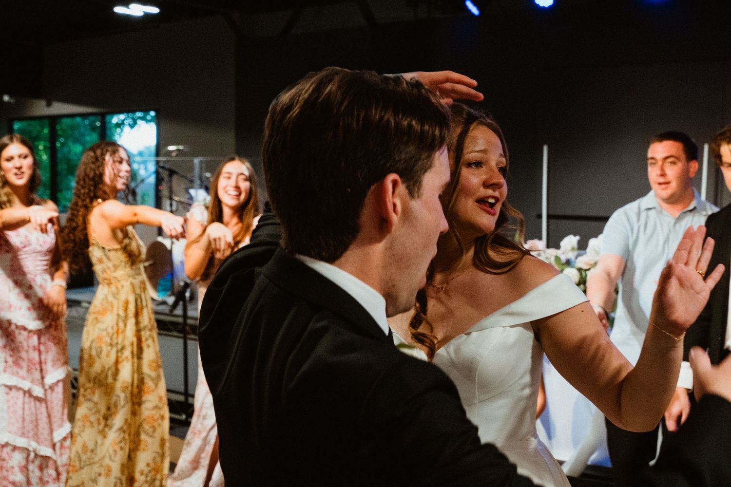 Bride and groom dancing joyfully with guests at a lively wedding reception celebration.
