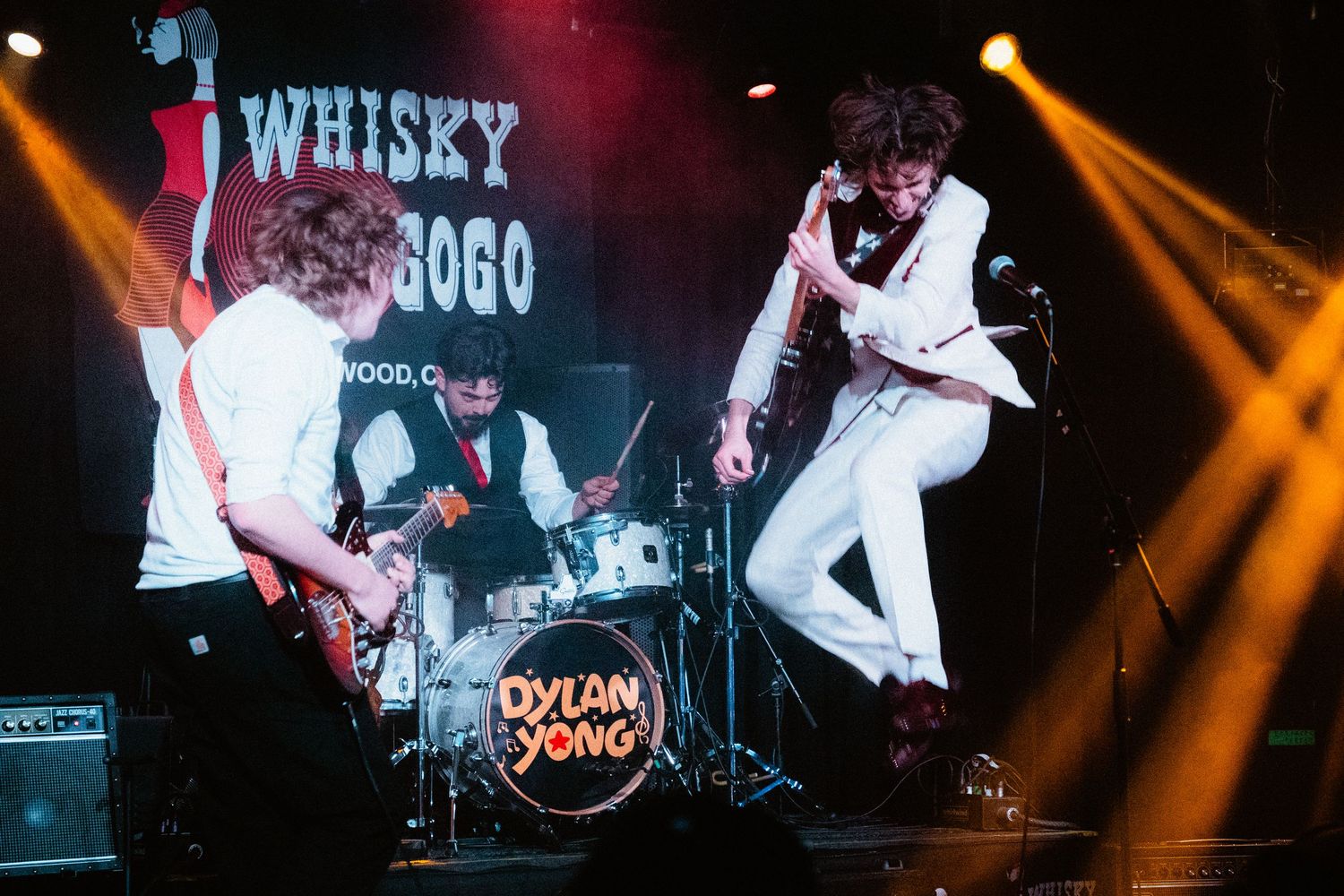 Rock band performing energetically on stage at the Whisky a Go Go with guitarist jumping.
