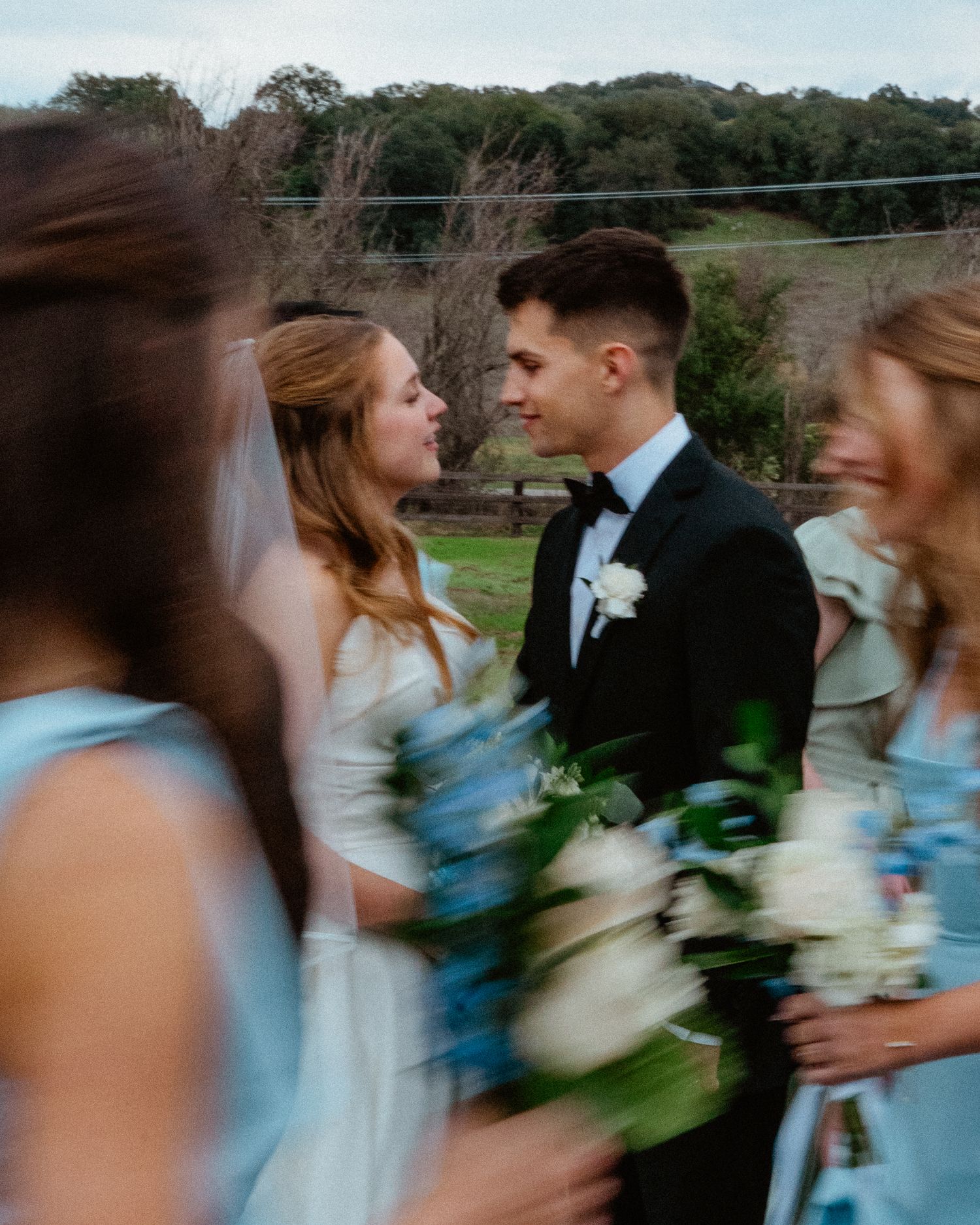 Bride and groom sharing an intimate glance surrounded by bridesmaids in light blue dresses.