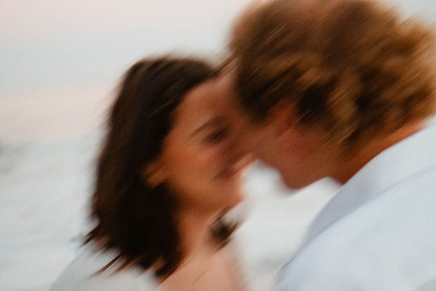 Blurry romantic couple almost kissing on a beach at sunset in an artistic motion blur photo.
