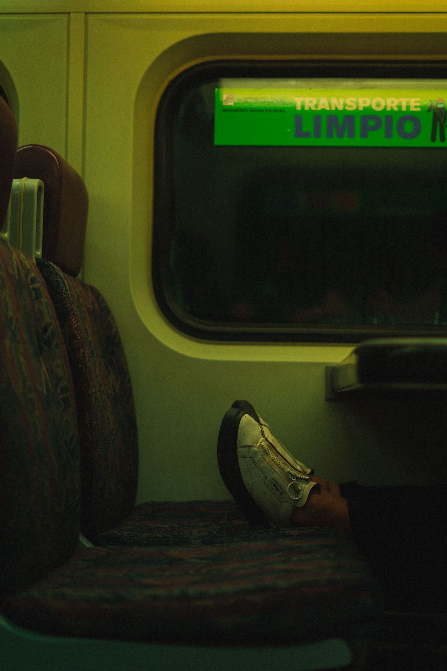 Empty seats on a dimly lit train with a green Transporte Limpio sign visible.
