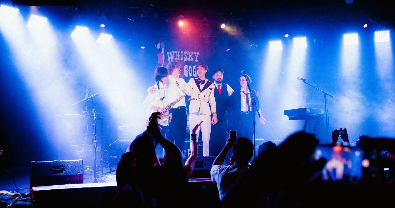 Band performing on stage at the Whisky a Go Go venue under blue spotlights with audience.