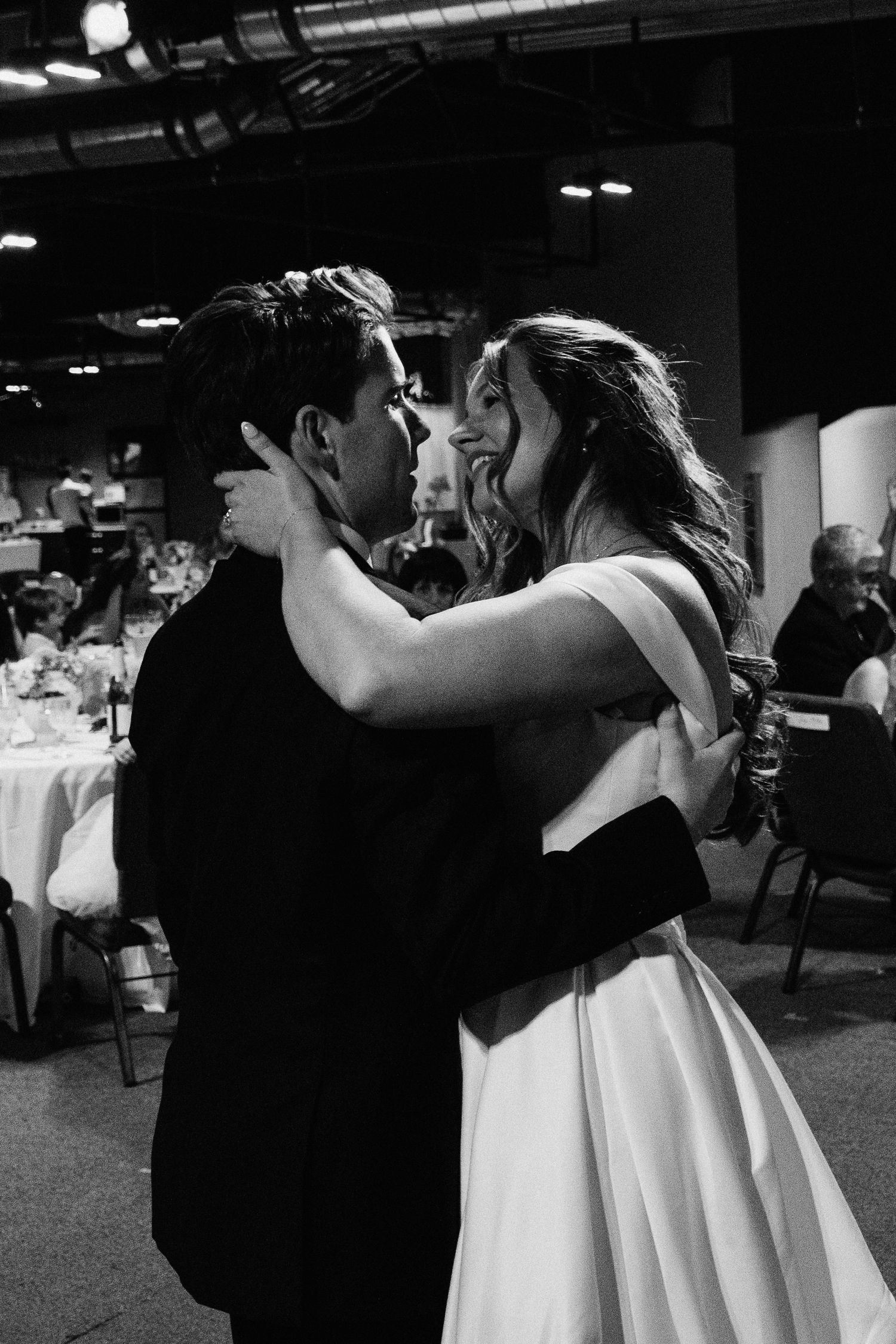 Black and white photo of a bride and groom sharing their first dance at a wedding reception.