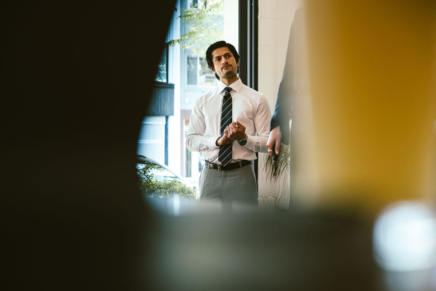 Business professional in white shirt and tie presenting at a blackboard in a modern office setting.