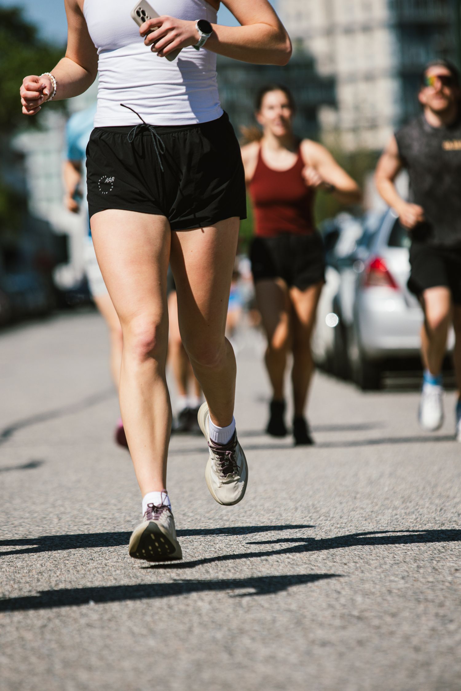 Runners in athletic wear jogging on a sunny city street during an outdoor race event.
