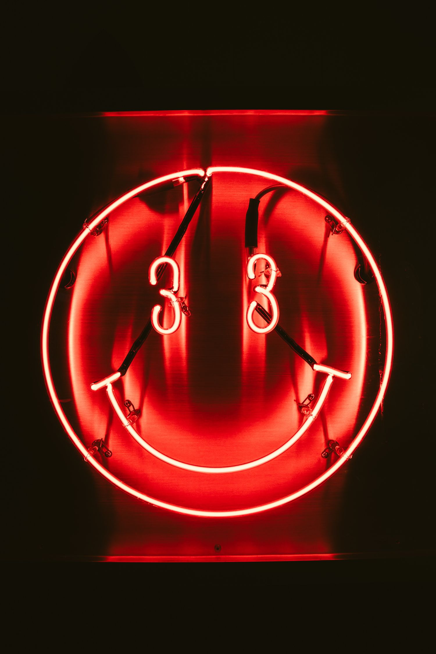 Red neon smiley face sign with number 33 eyes glowing in the dark.