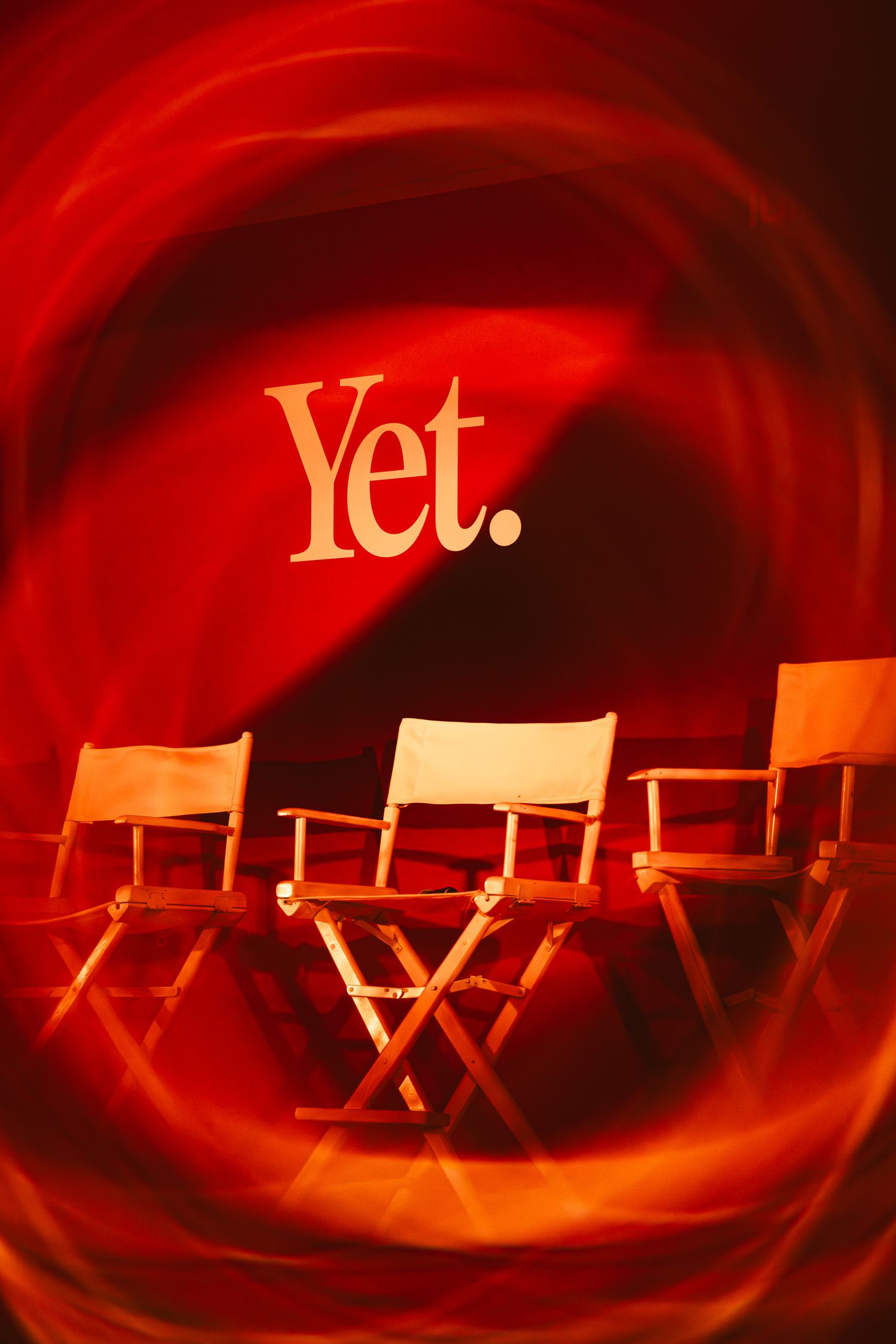 Three director's chairs on a red-lit stage with 'Yet.' text backdrop at a lululemon event.