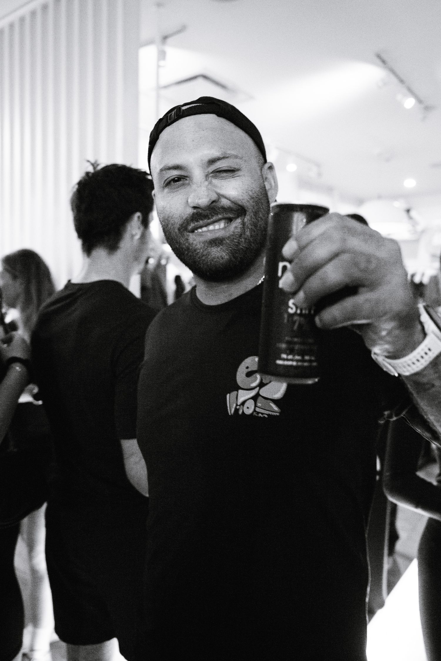 Smiling bearded man holding a drink at a social event in black and white photo.