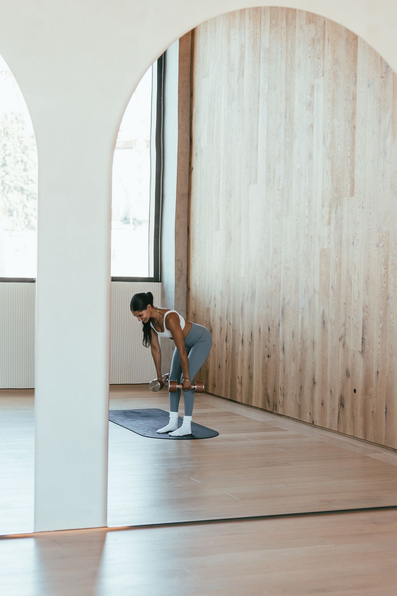 Woman exercising with resistance bands on a yoga mat in a bright studio.