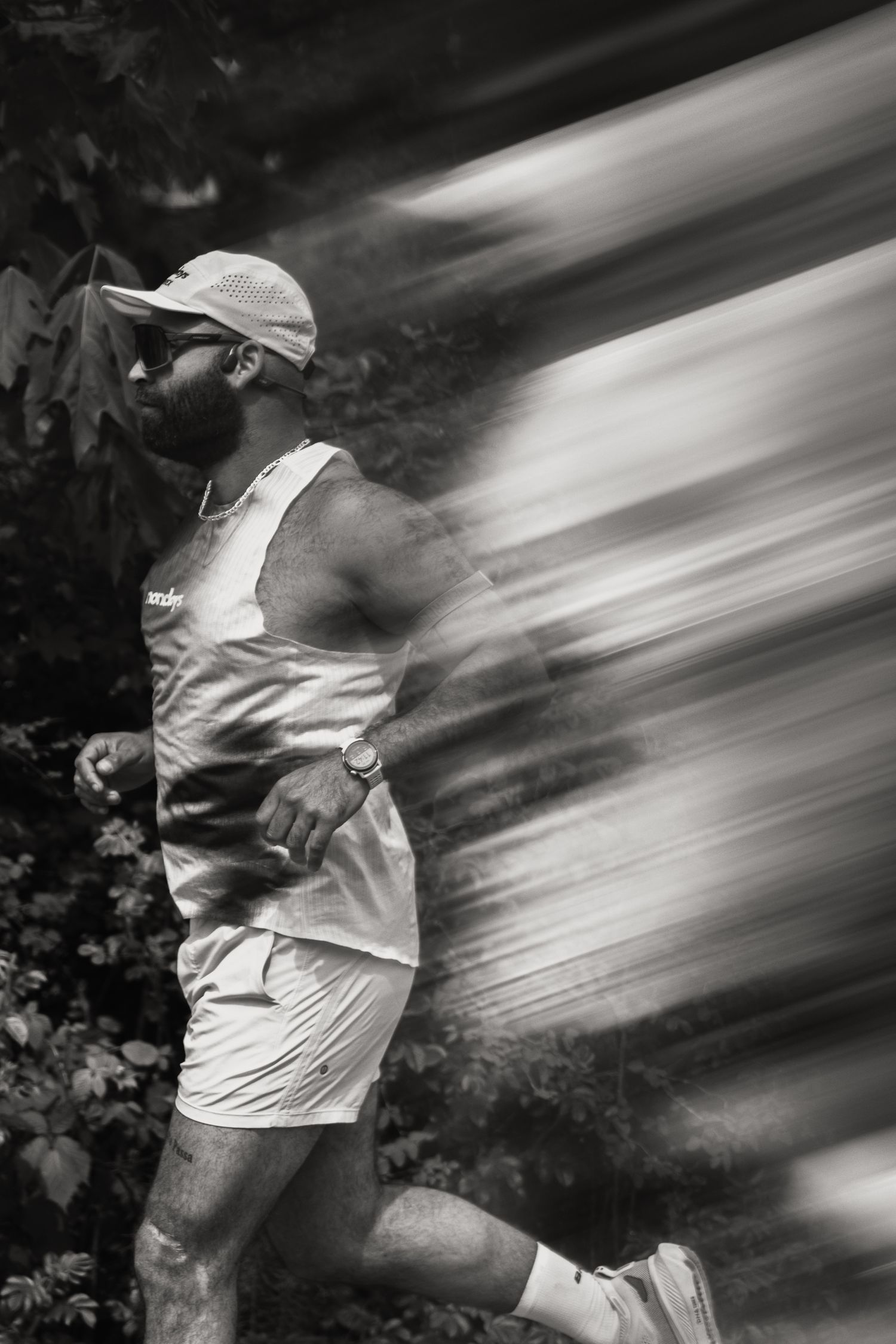 Black and white motion blur photo of bearded man running in athletic gear.