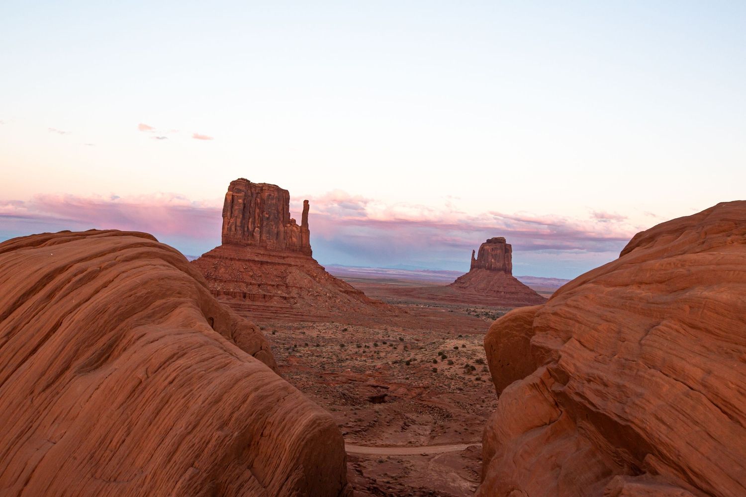 Stunning sunset view of Monument Valley buttes rising above red sandstone formations in the Arizona desert.