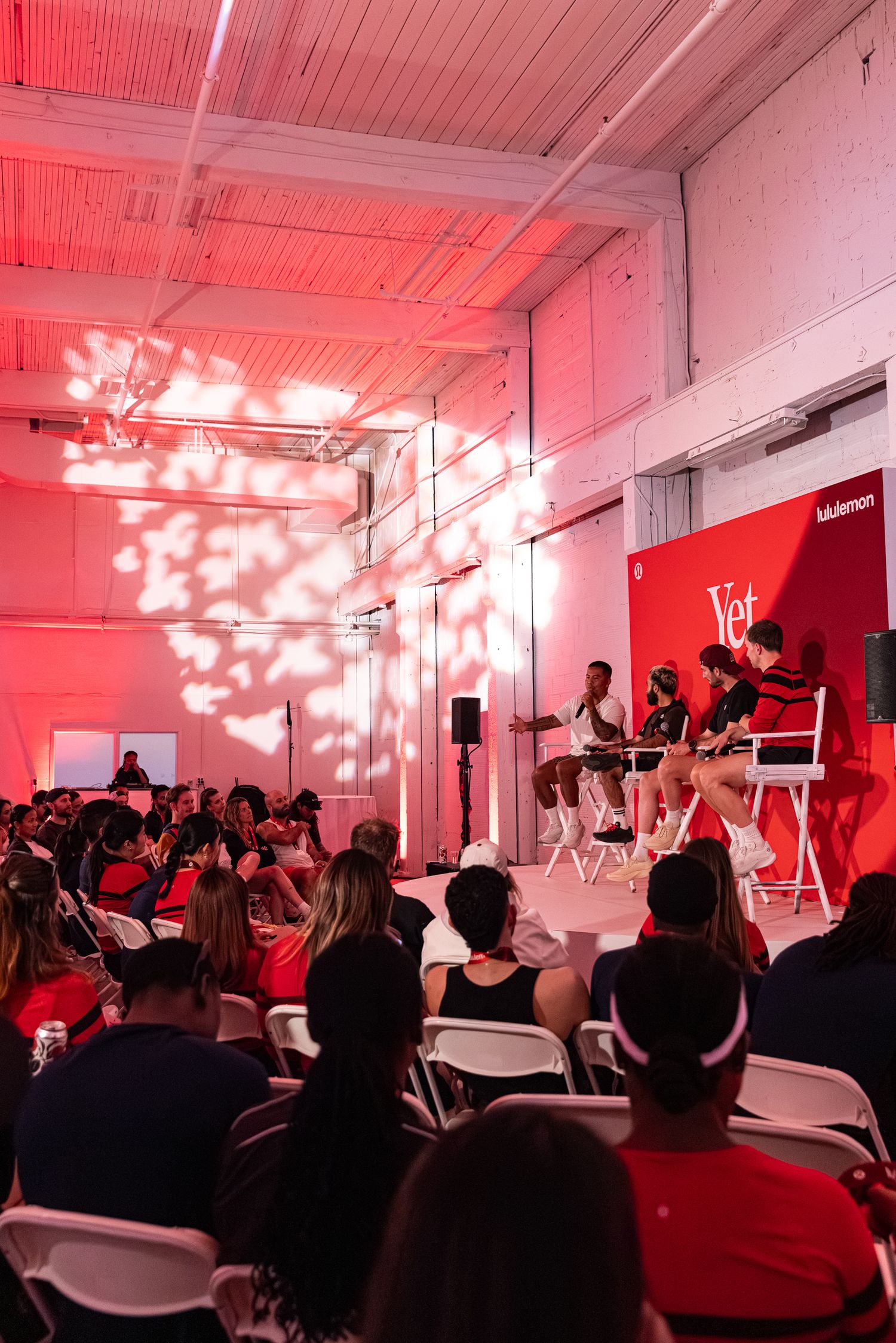 Audience seated at a Lululemon panel discussion event with red lighting and brand signage.