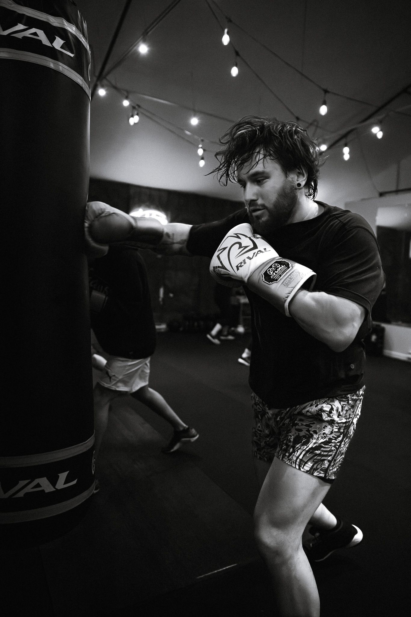 Black and white photo of a male boxer hitting a Rival punching bag during an intense training session.