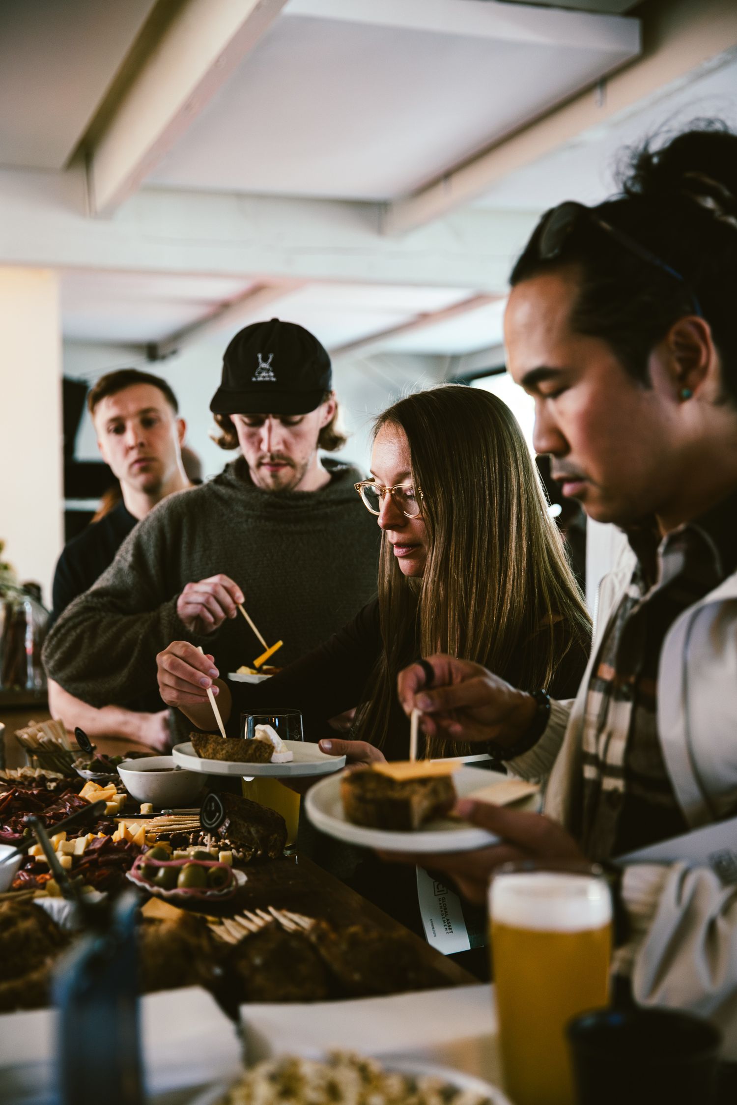 Group of people serving themselves food at a buffet table with drinks, enjoying a casual dining experience together.