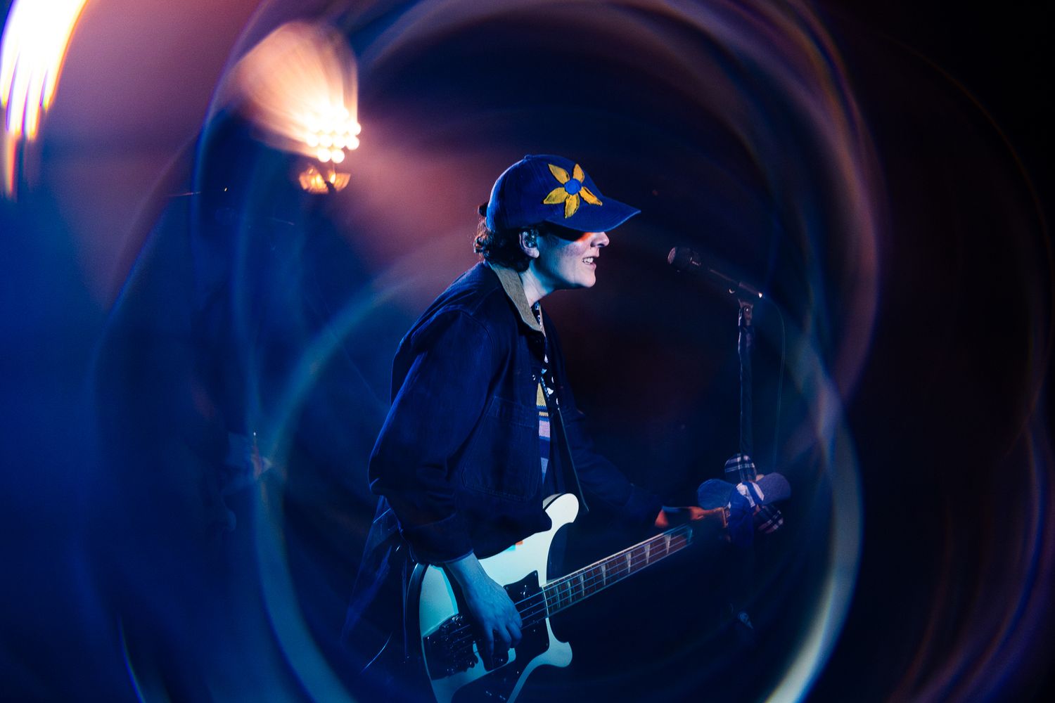 Guitarist on stage captured through a swirling lens effect with vivid blue stage lights in the background.
