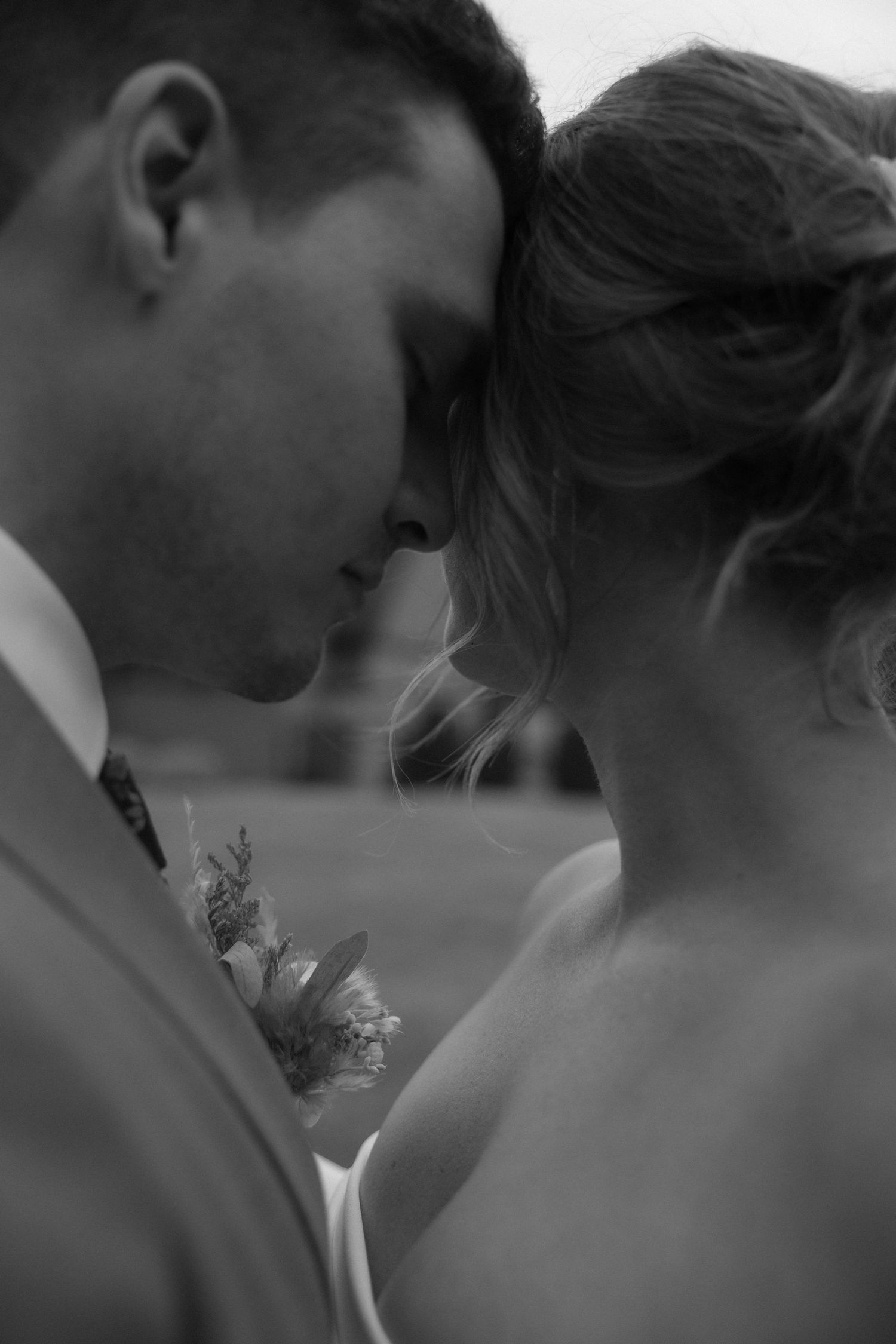 Intimate black and white close-up of bride and groom touching foreheads tenderly on wedding day.