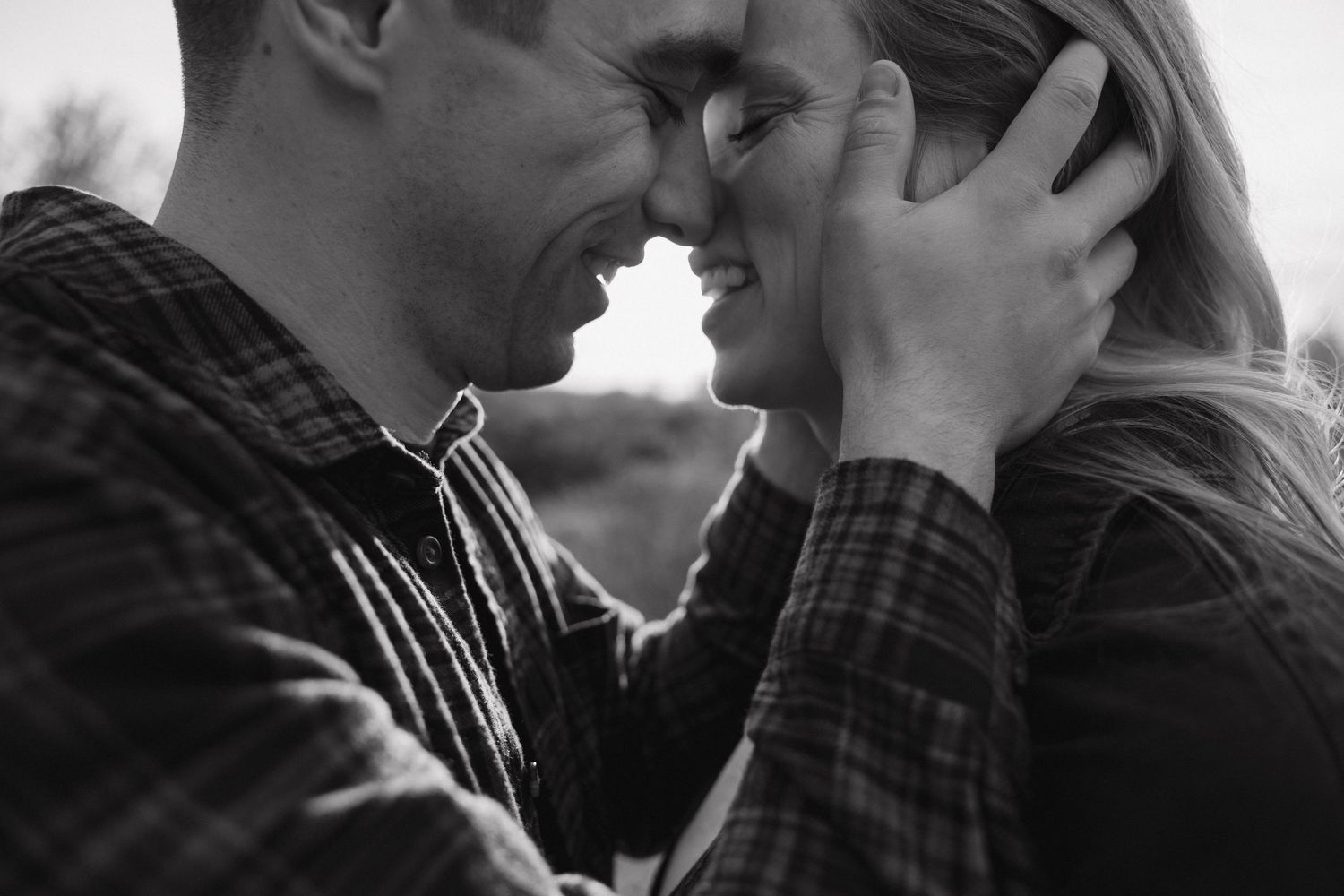 Black and white close-up of a smiling couple touching foreheads tenderly in an intimate romantic moment.