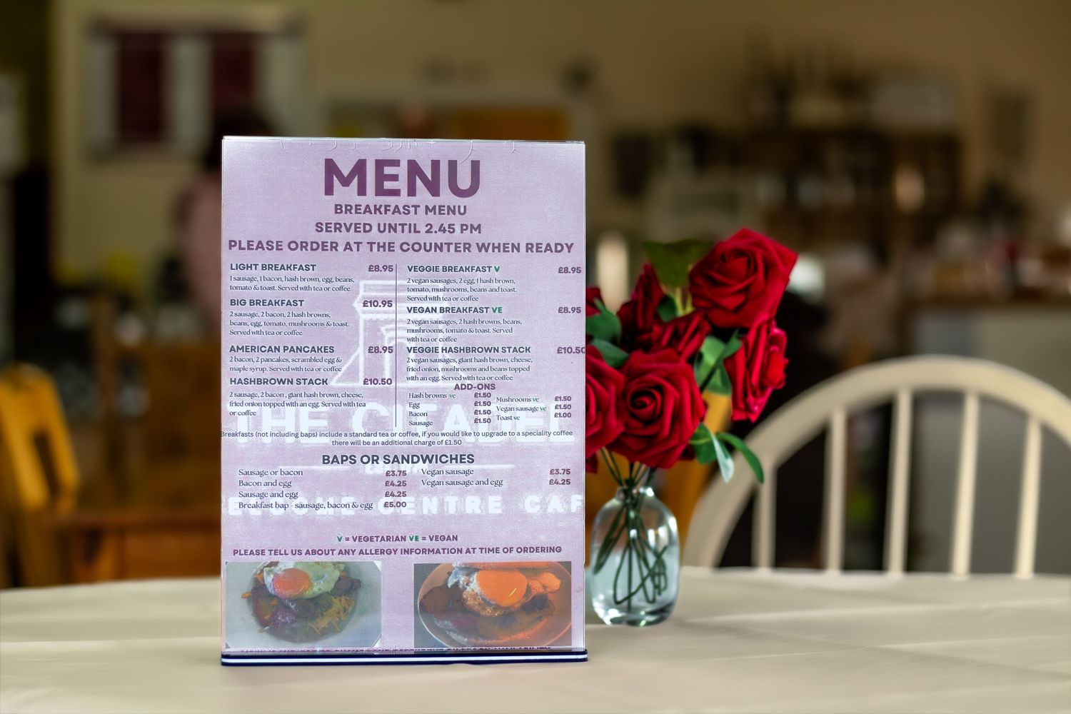Restaurant menu displayed on a table with red roses in the background.