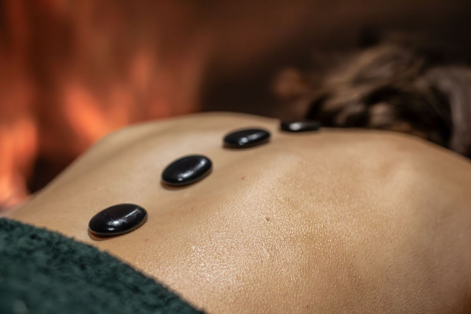 Close-up of hot stones placed on back during therapeutic massage treatment.