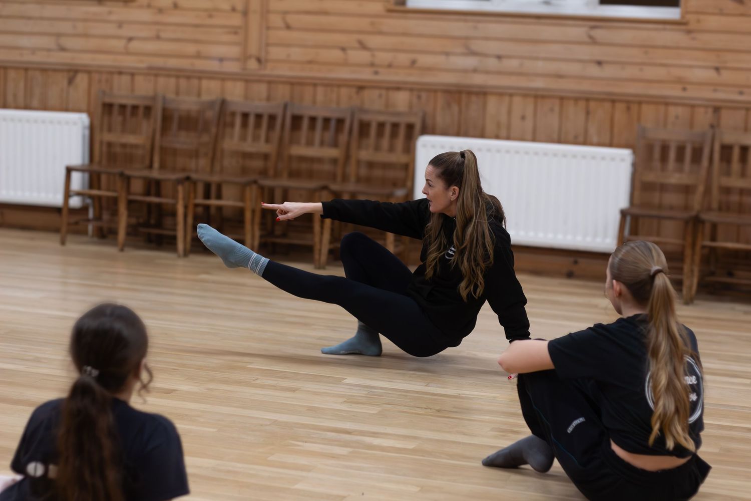 Dancers practicing choreography on a wooden studio floor.