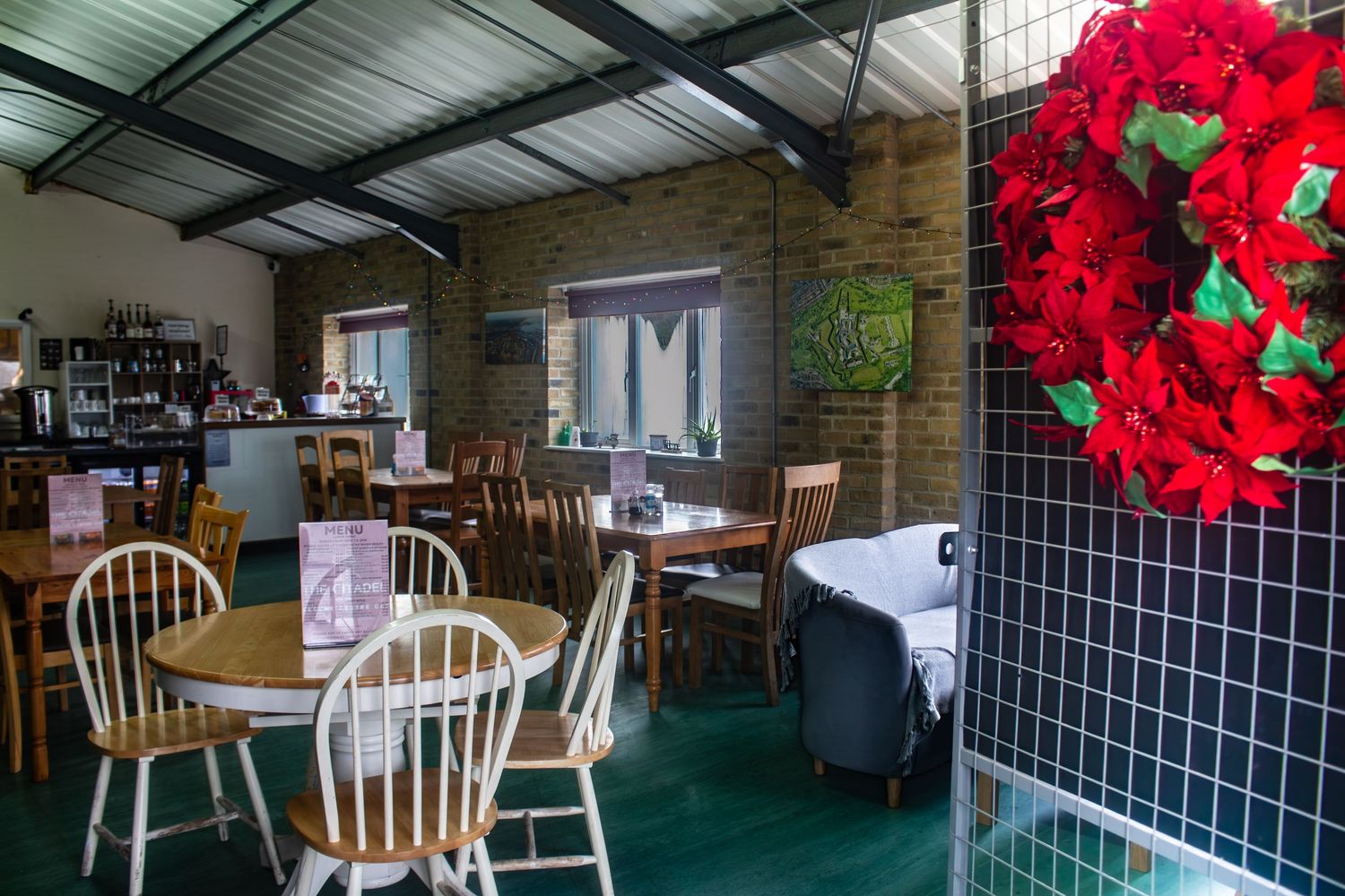 Interior of a cafe with wooden chairs and red floral decorations.